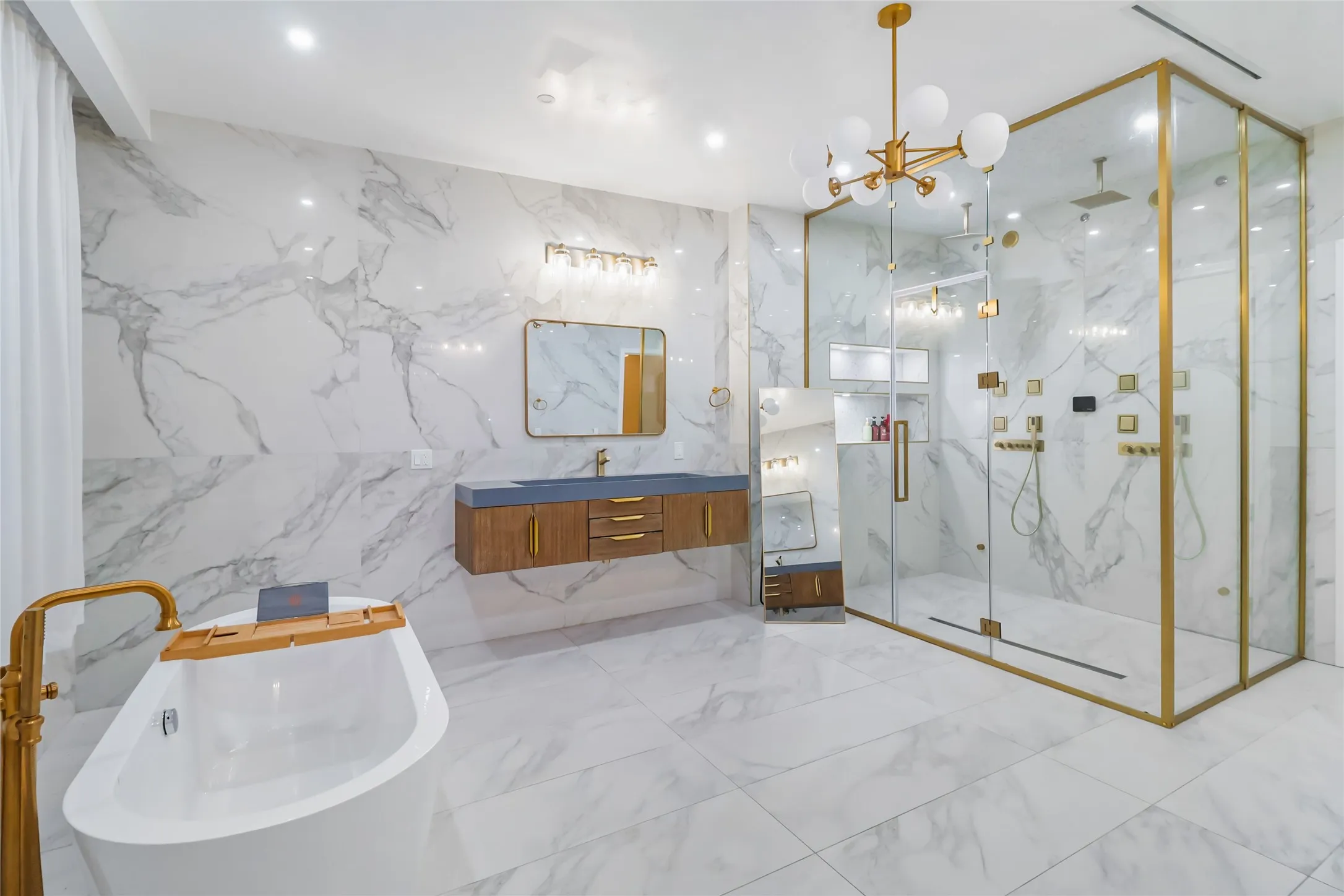Full bath featuring a marble finish shower, vanity, a freestanding bath, tile walls, and stone wall