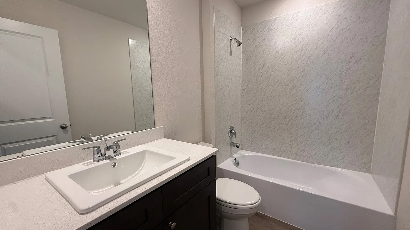 Bathroom featuring a dark wood-finish vanity, white countertop, and integrated sink with chrome fixtures
