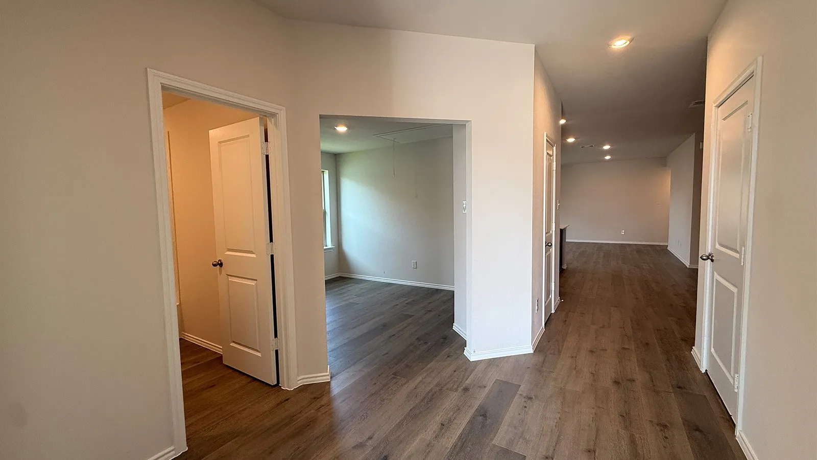 Hallway featuring wood-finish flooring, recessed lighting, and white paneled doors