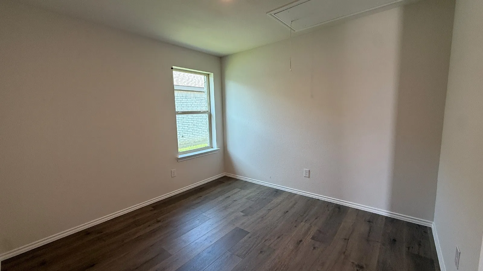 Interior room featuring wood-finish flooring, light neutral wall paint, and white baseboards