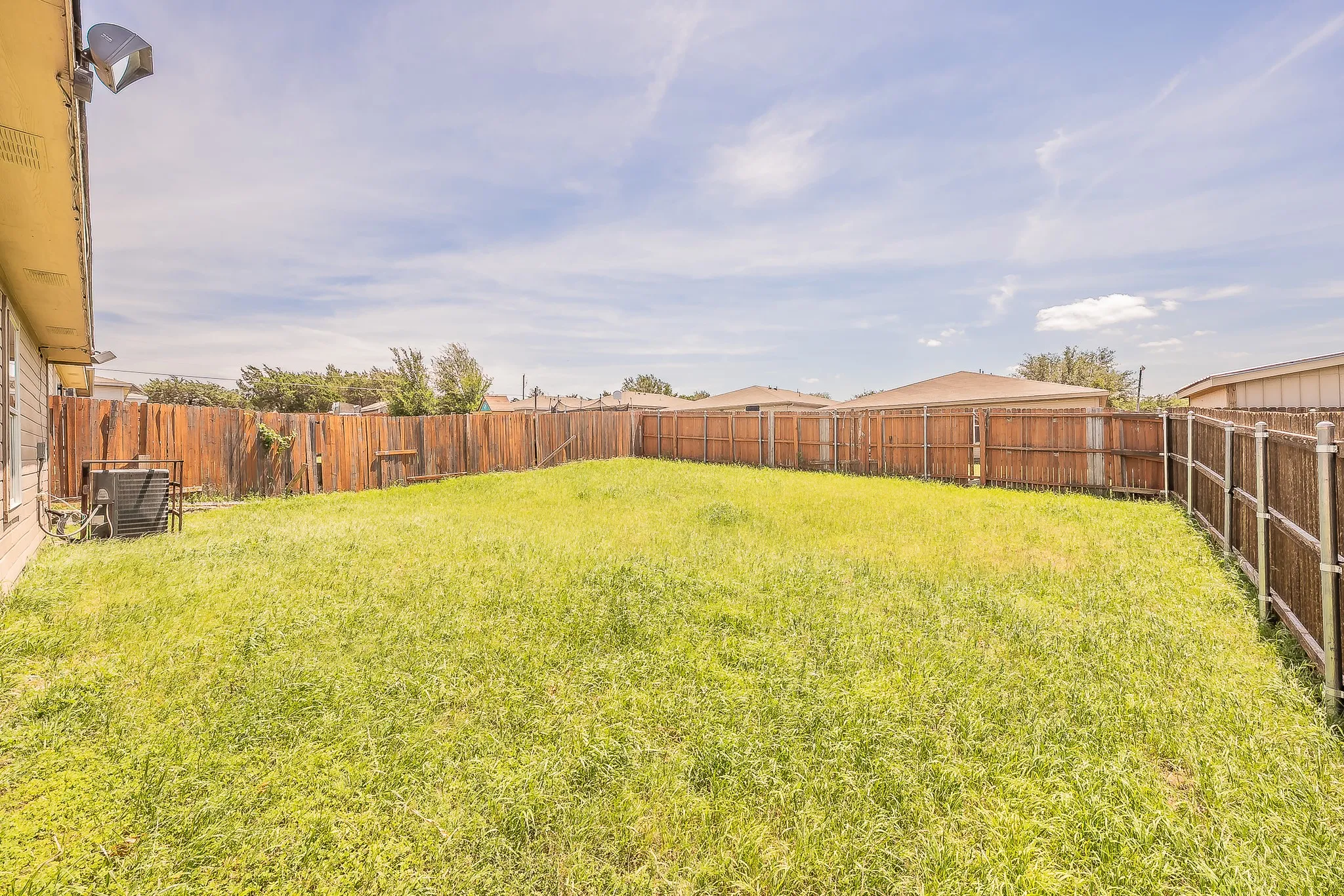 Expansive grassy yard with full privacy fencing