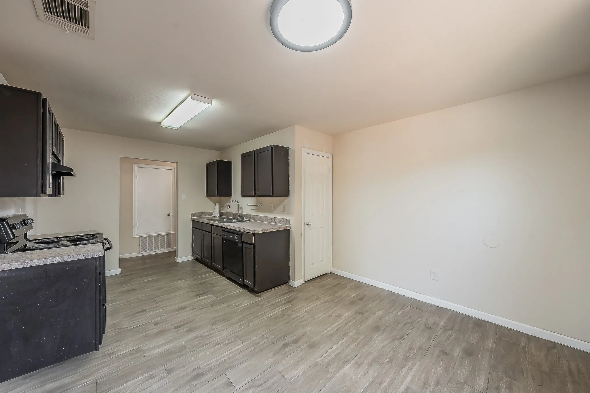 Kitchen space featuring wood-finish flooring, dark cabinetry, and light countertops