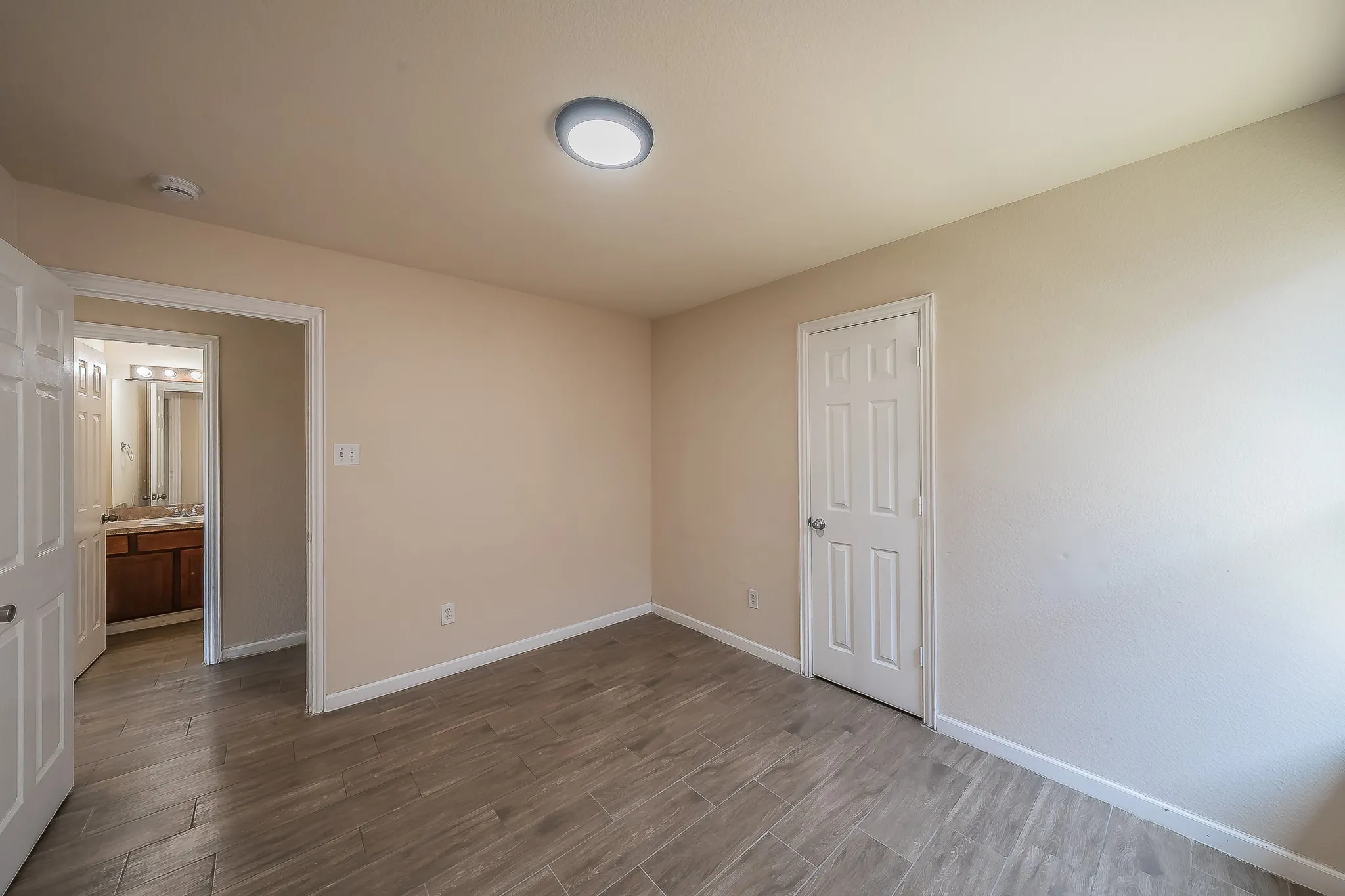 Neutral-toned interior room featuring wood-look tile flooring, light-colored walls, and a flush-mount ceiling light fixture