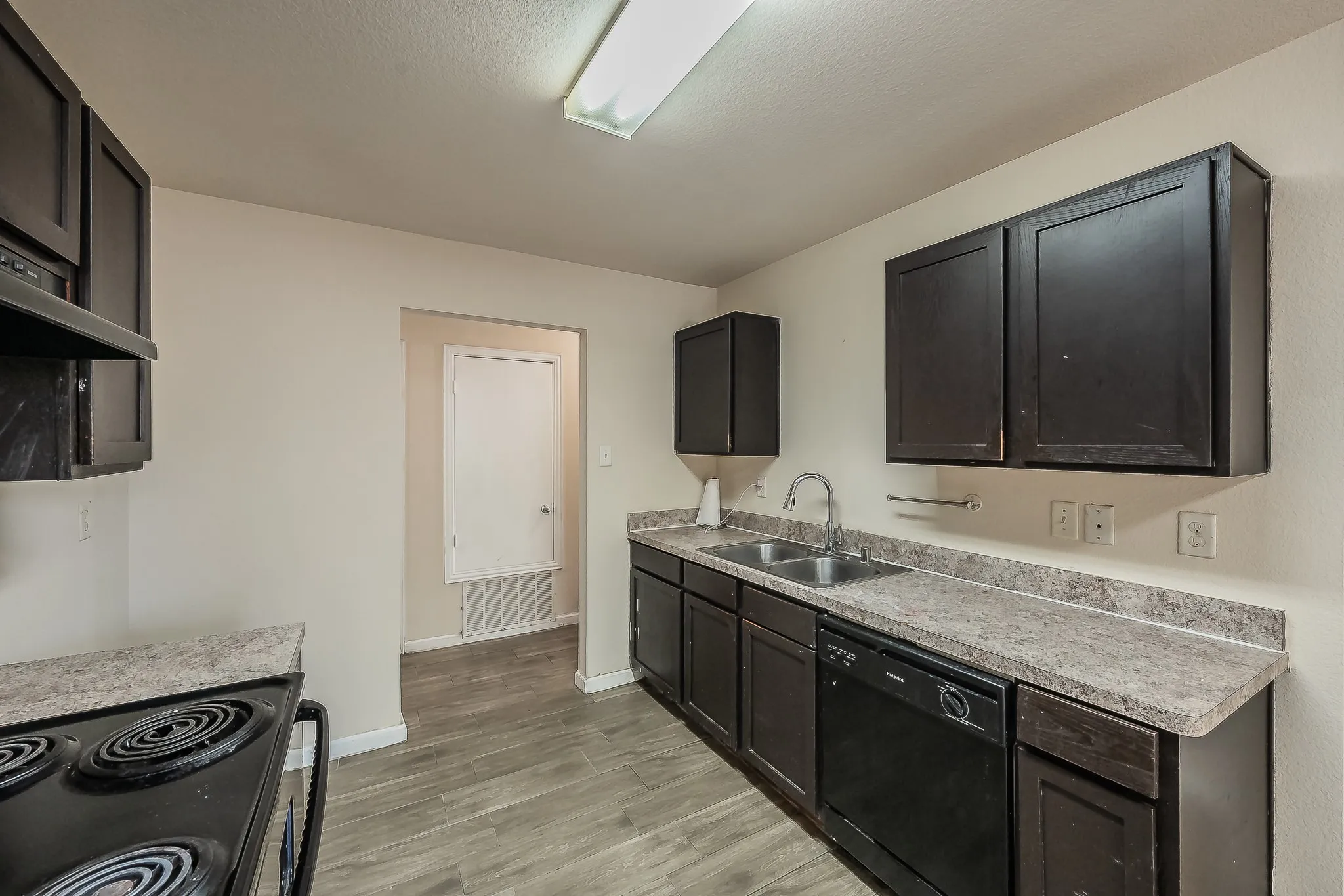 Kitchen featuring dark wood-finish cabinetry, a black electric range, and a dual basin stainless steel sink