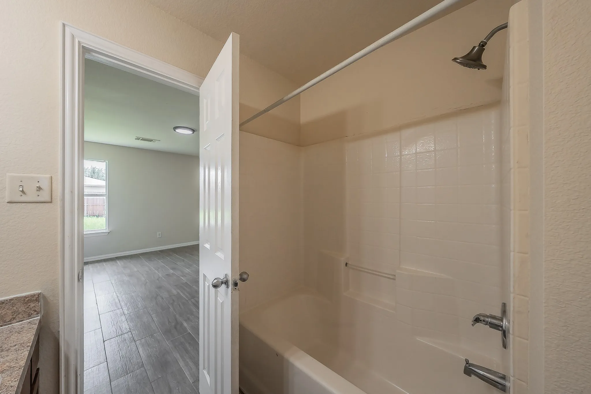 White bathtub and shower combination with a brushed nickel showerhead and faucet