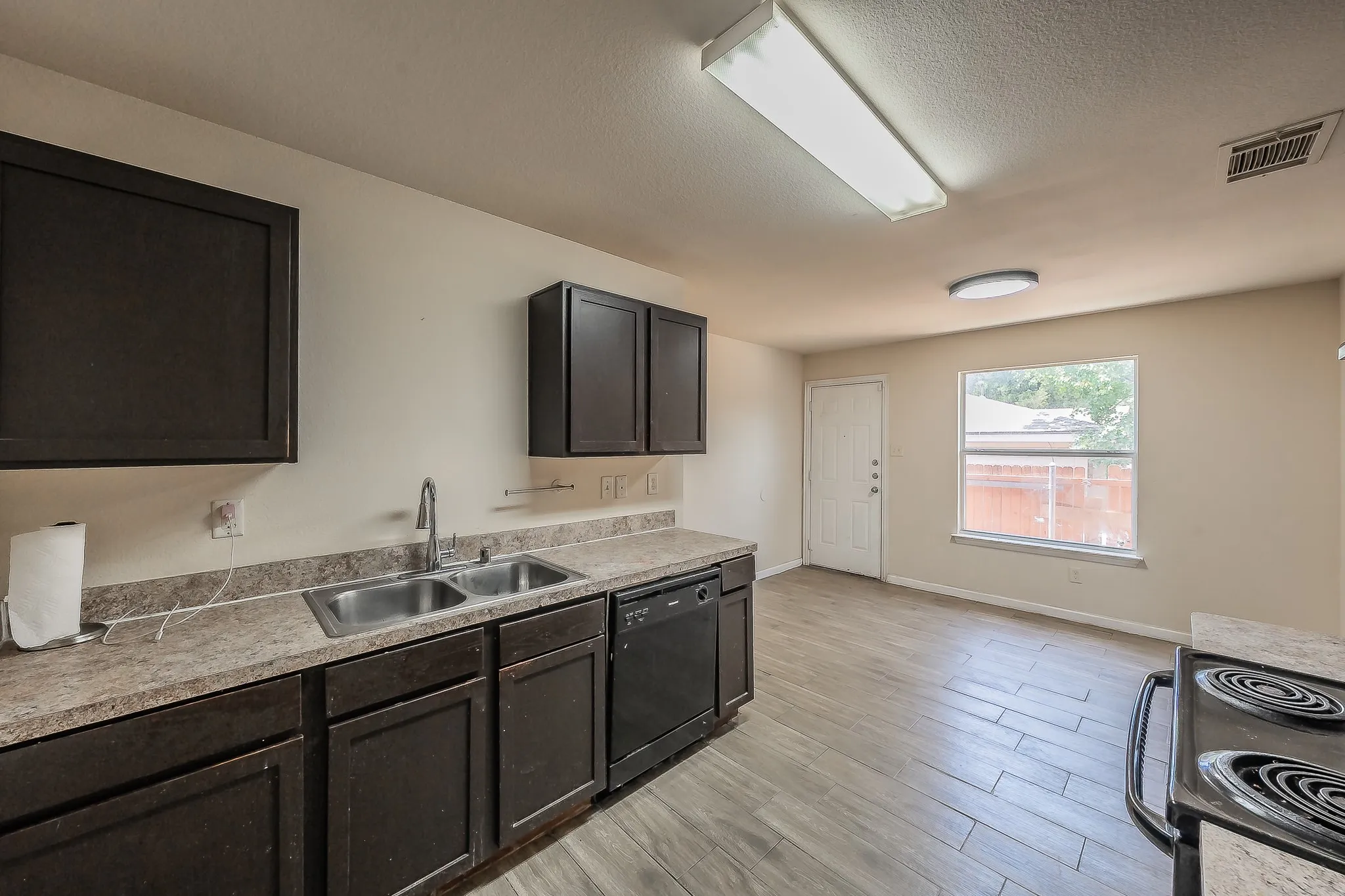 Kitchen featuring wood-finish flooring, dark cabinetry, and light-toned countertops