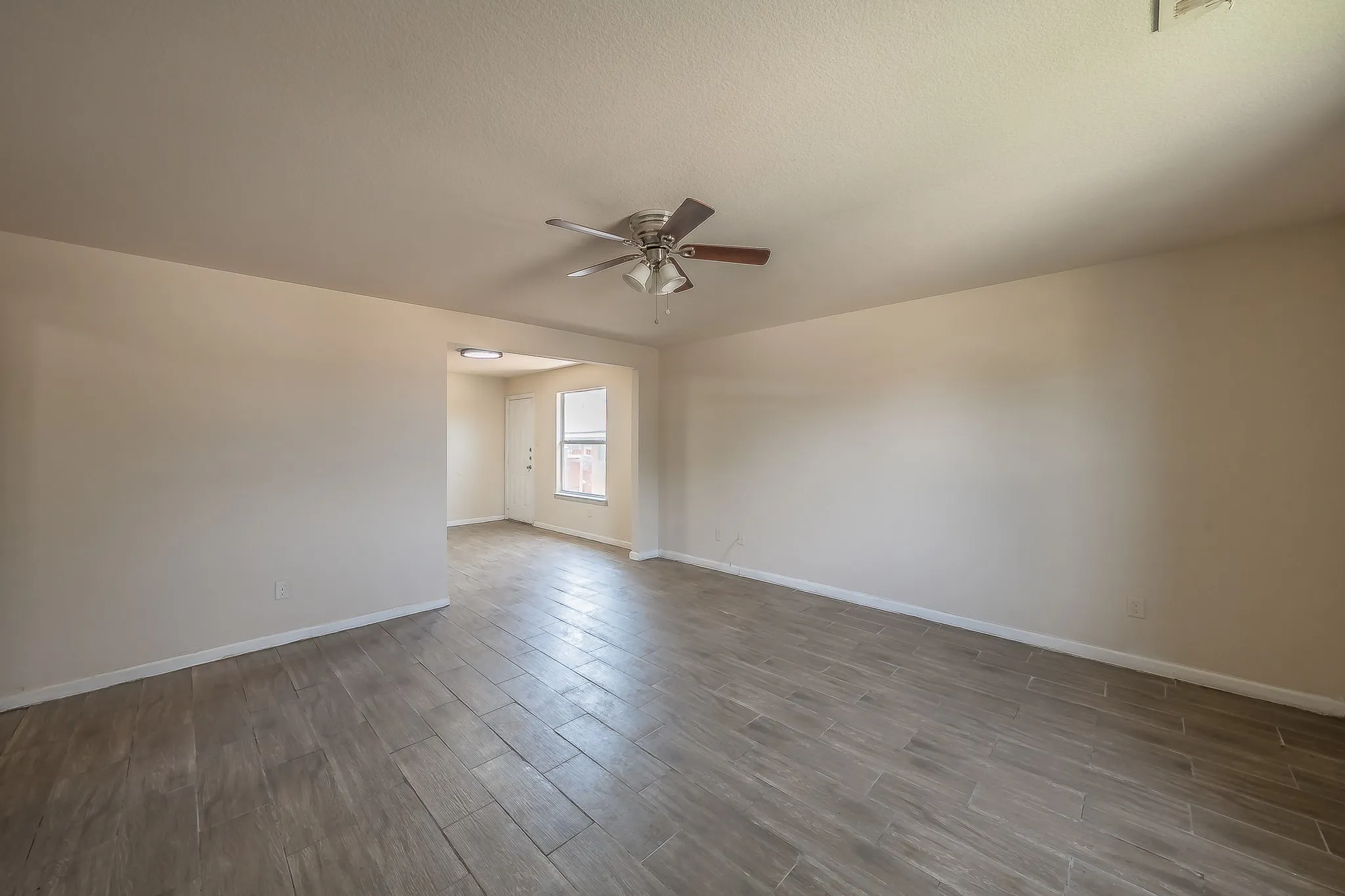 Spacious interior featuring wood-look tile flooring and a ceiling fan with light fixture