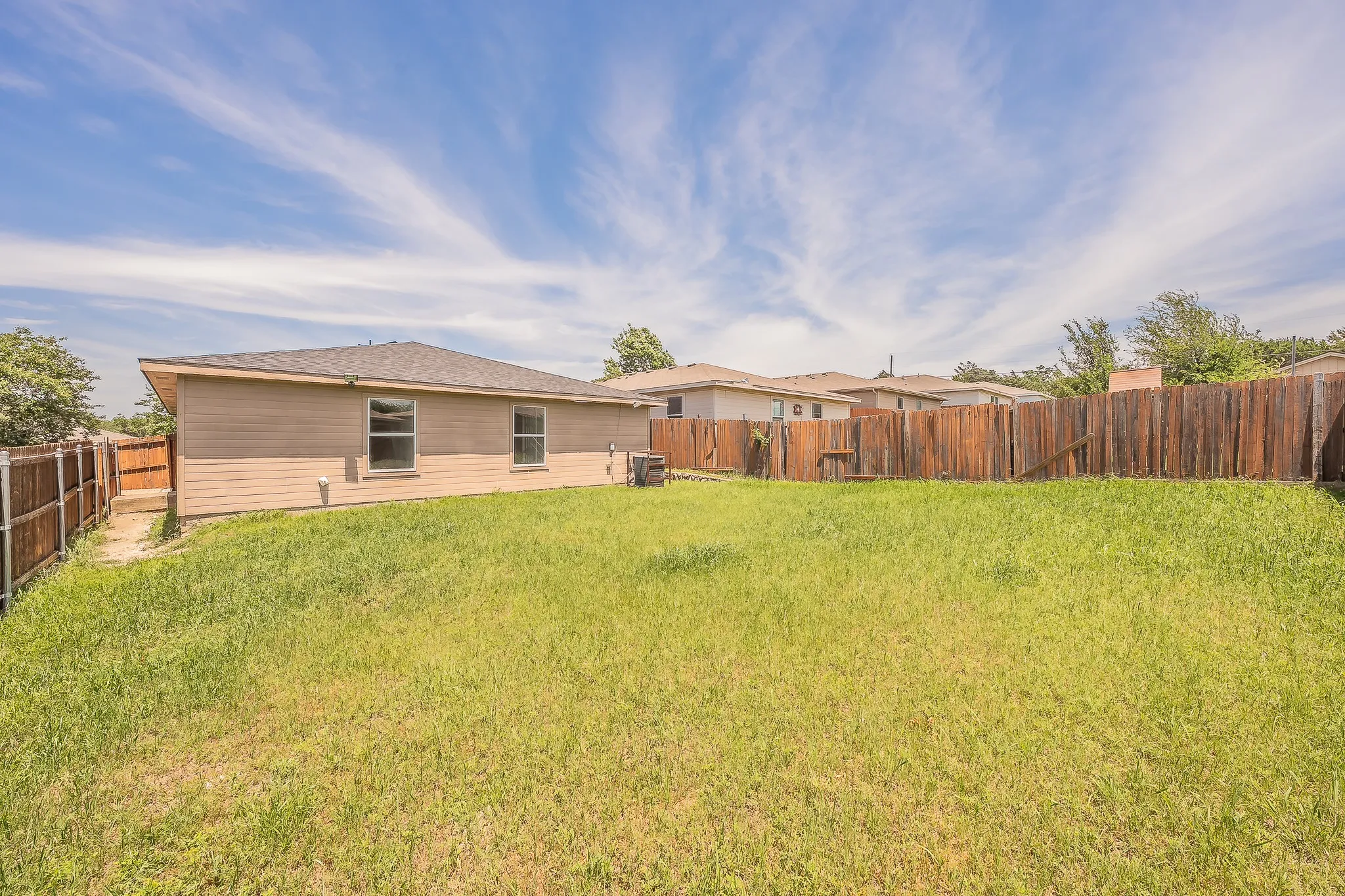 Expansive grassy yard area with a partial privacy fence
