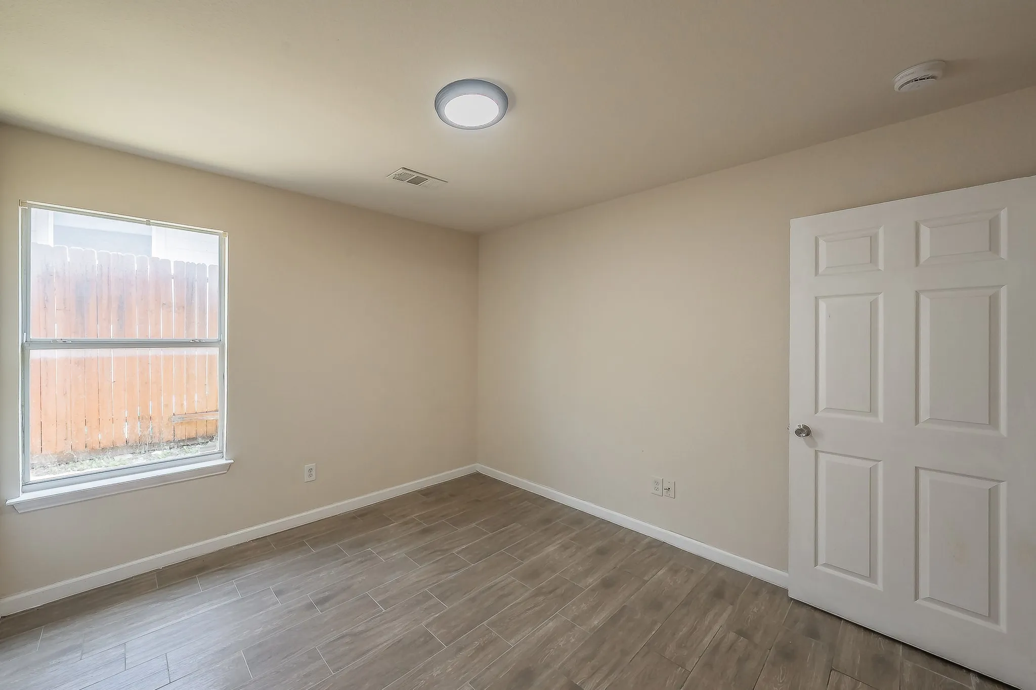 Room featuring wood-look tile flooring, neutral wall paint, and white baseboards