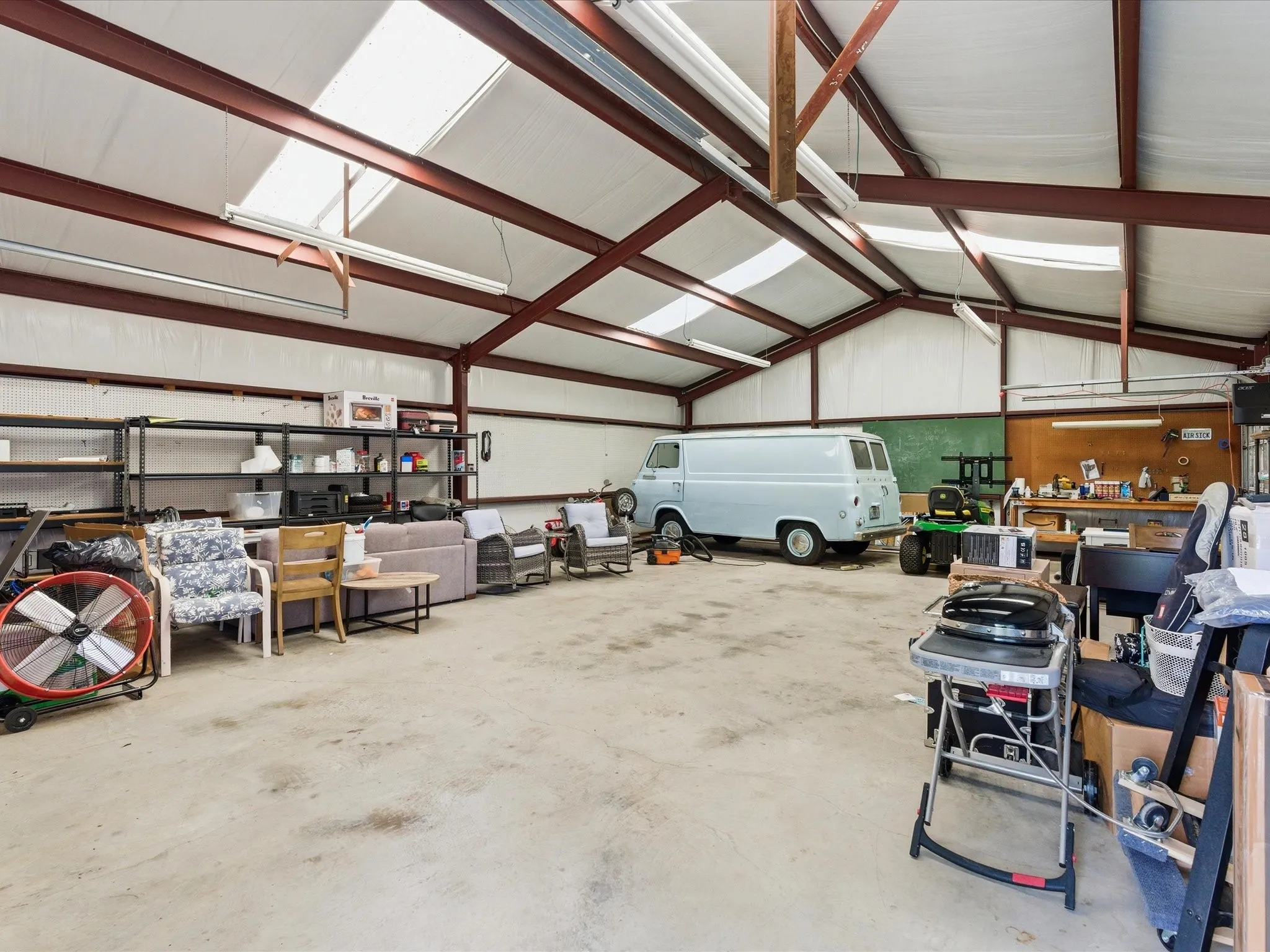Spacious interior with exposed metal beams and a concrete floor, offering ample room and skylight panels for natural light