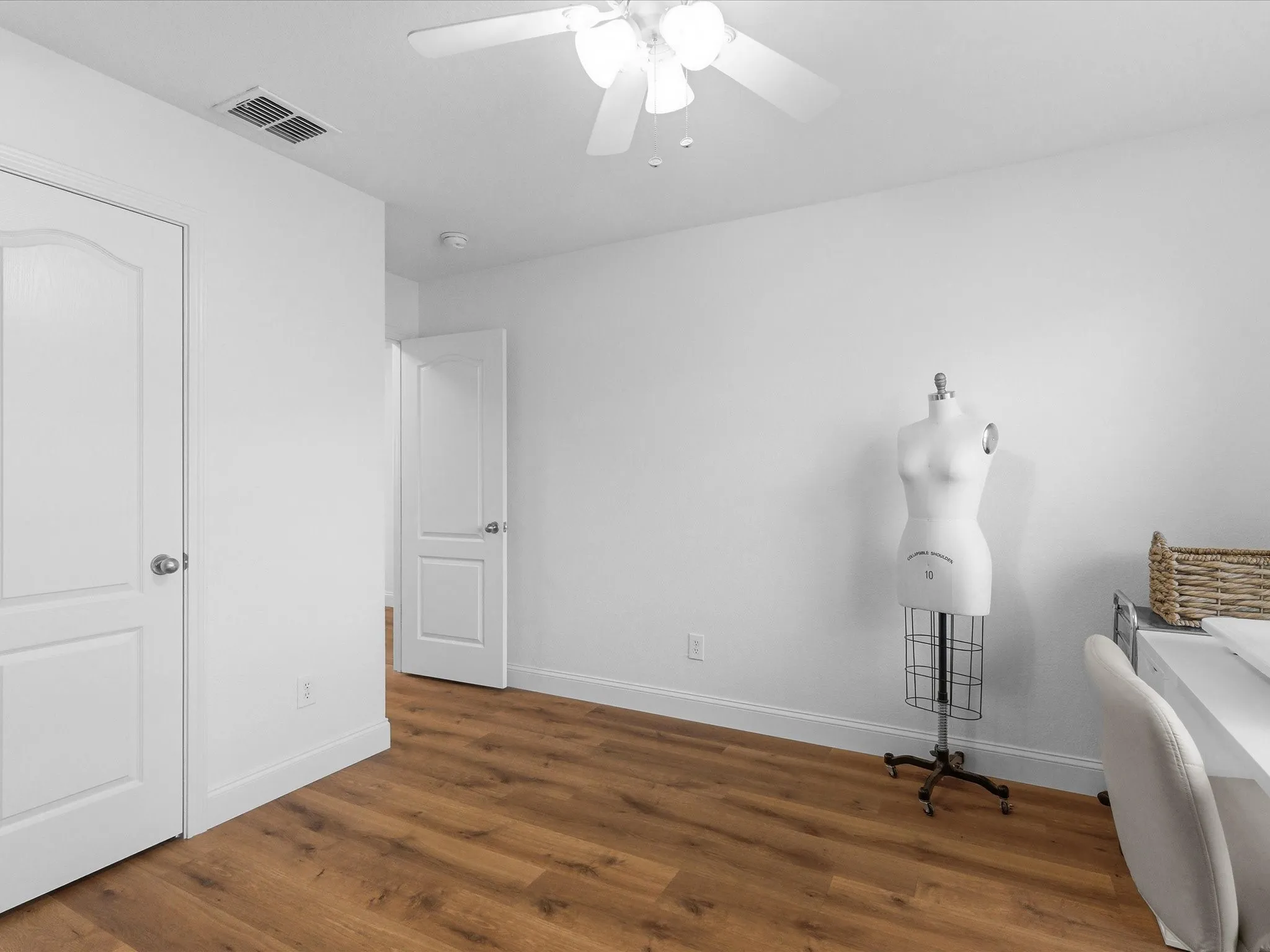 This room features hardwood style flooring, a ceiling fan with integrated lighting, and white walls