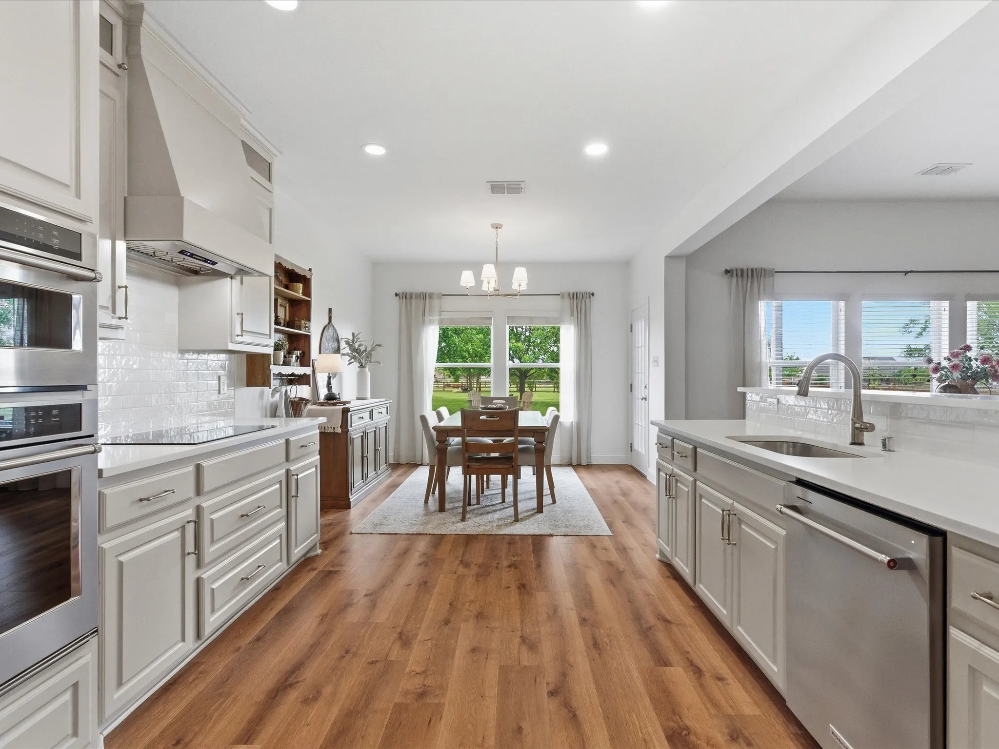 The kitchen features light-colored cabinetry, stainless steel appliances, and a tile backsplash