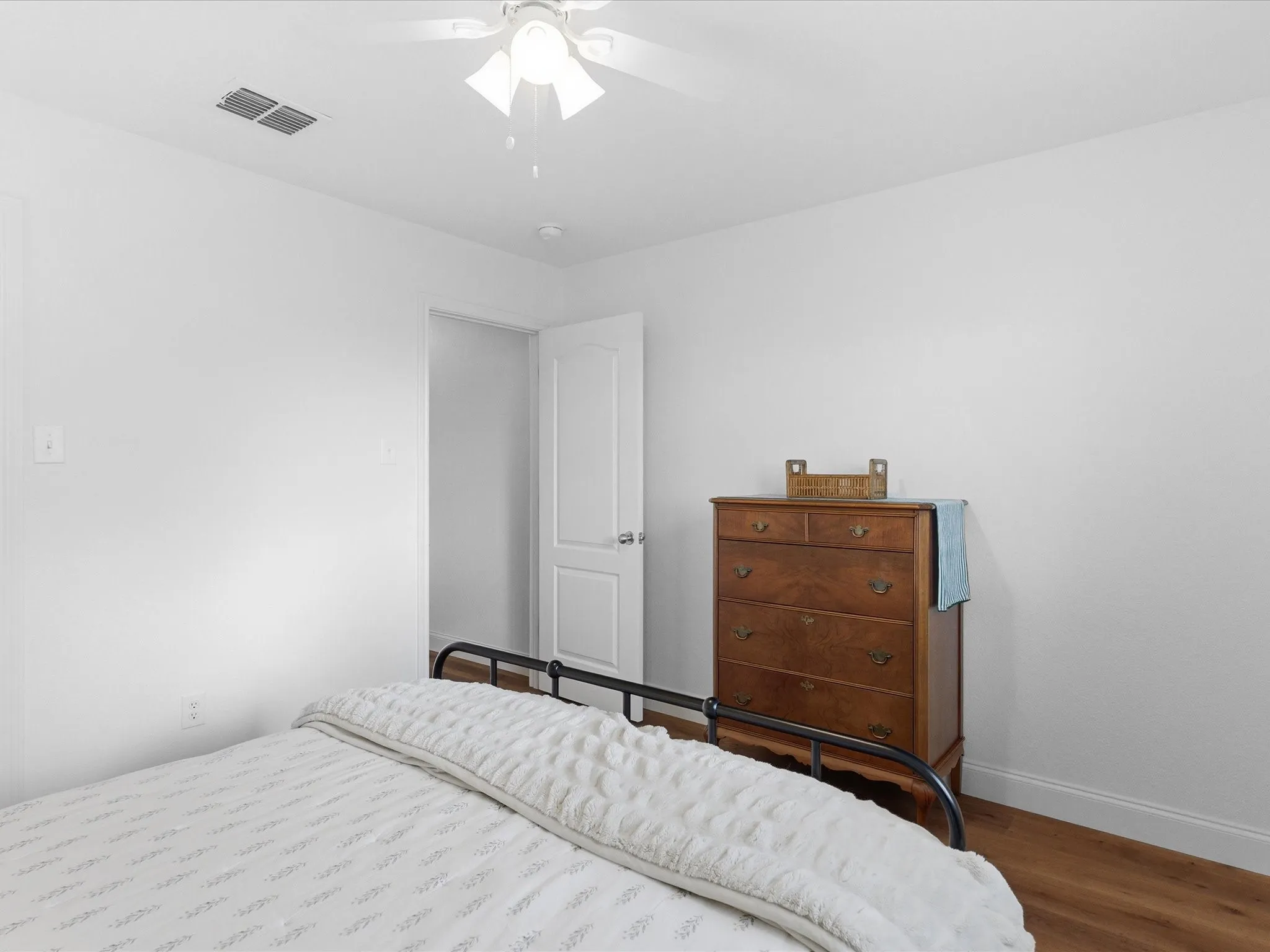 This room features a ceiling fan, light-colored walls, and wood-style flooring