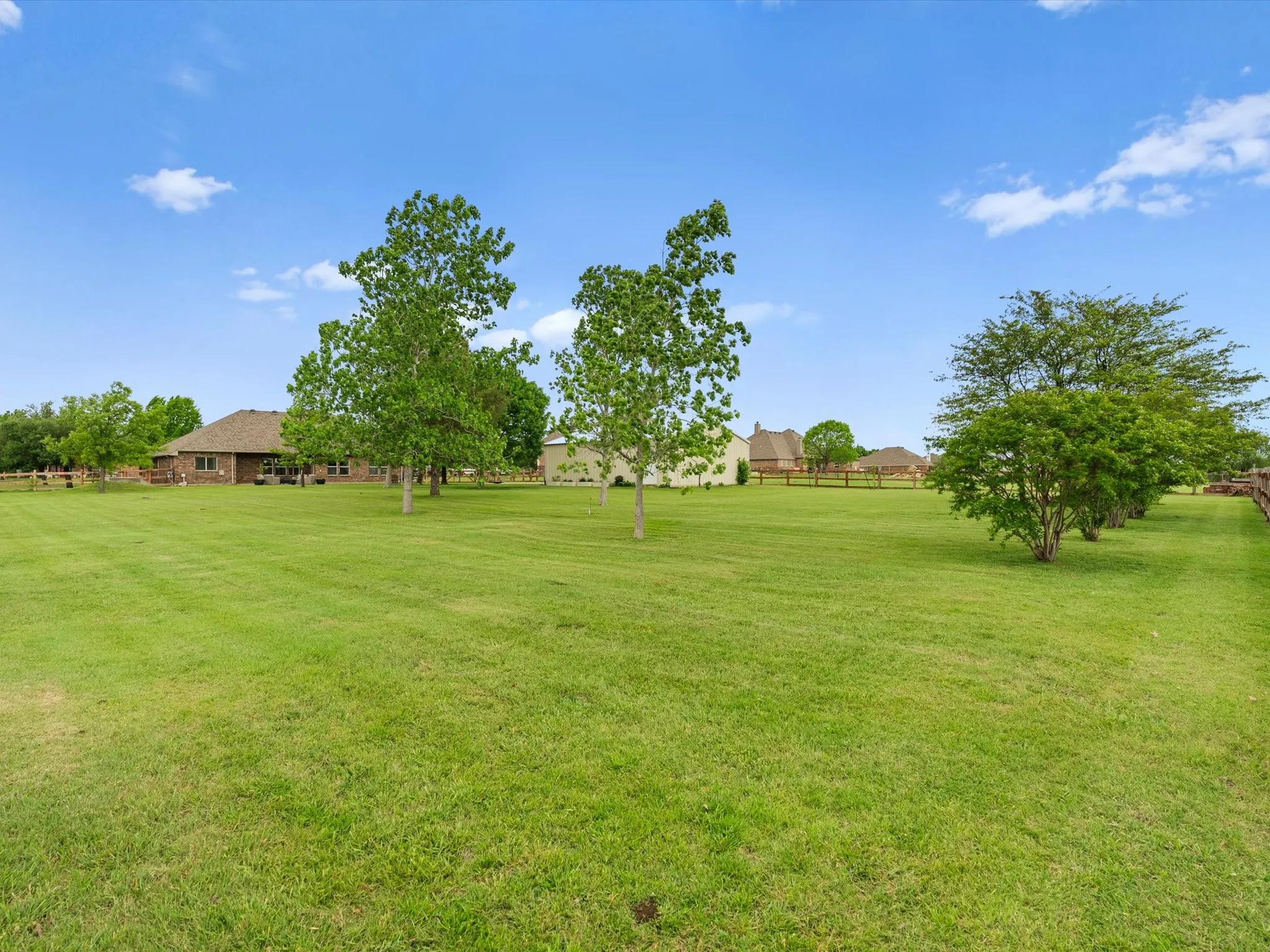 Expansive green lawn with mature trees and a partial view of the property's exterior