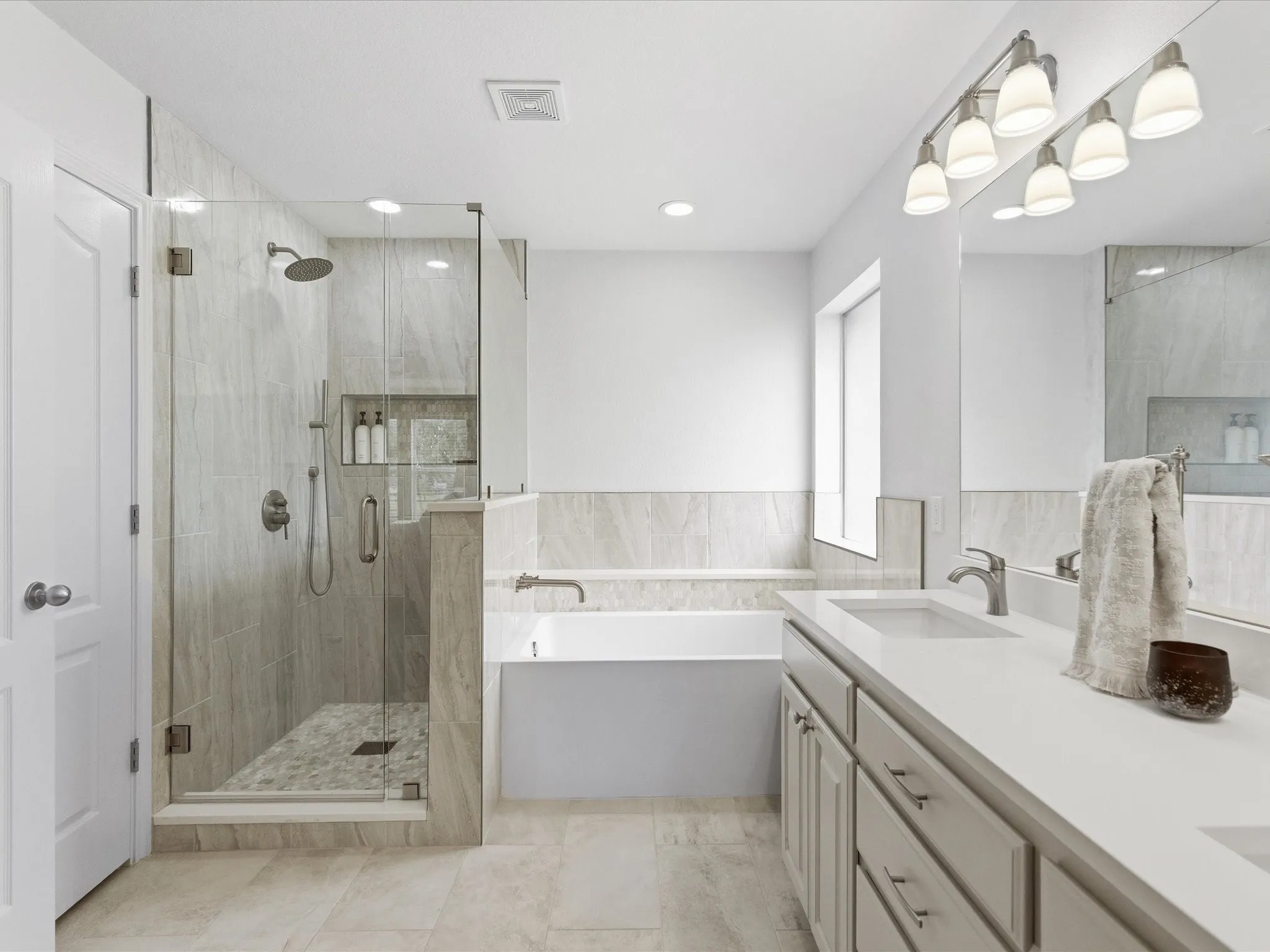 The bathroom features a spacious glass-enclosed shower with a rainfall showerhead, alongside a large bathtub