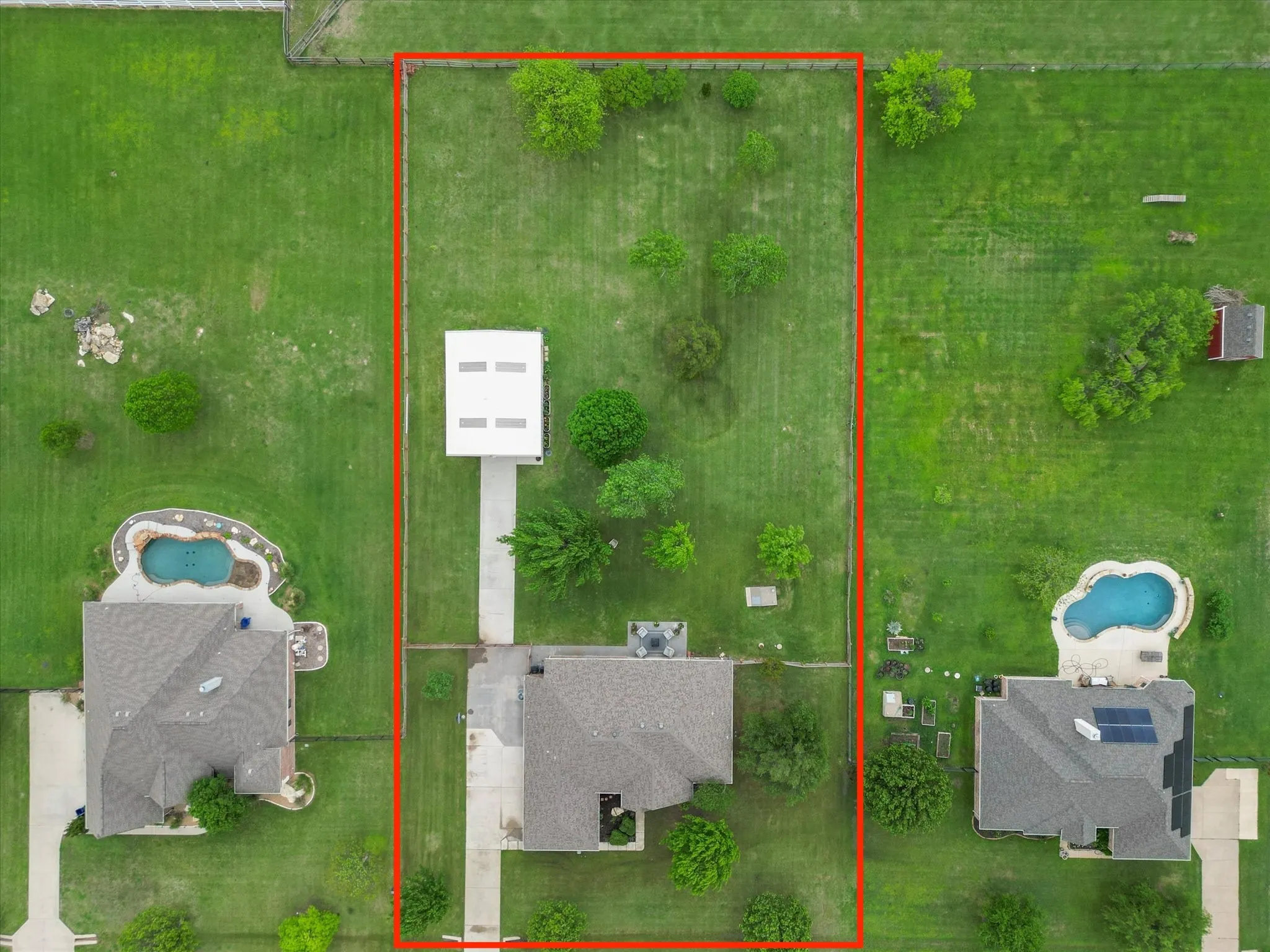 Aerial view of the property, showcasing an extensive lawn with mature trees and a detached structure