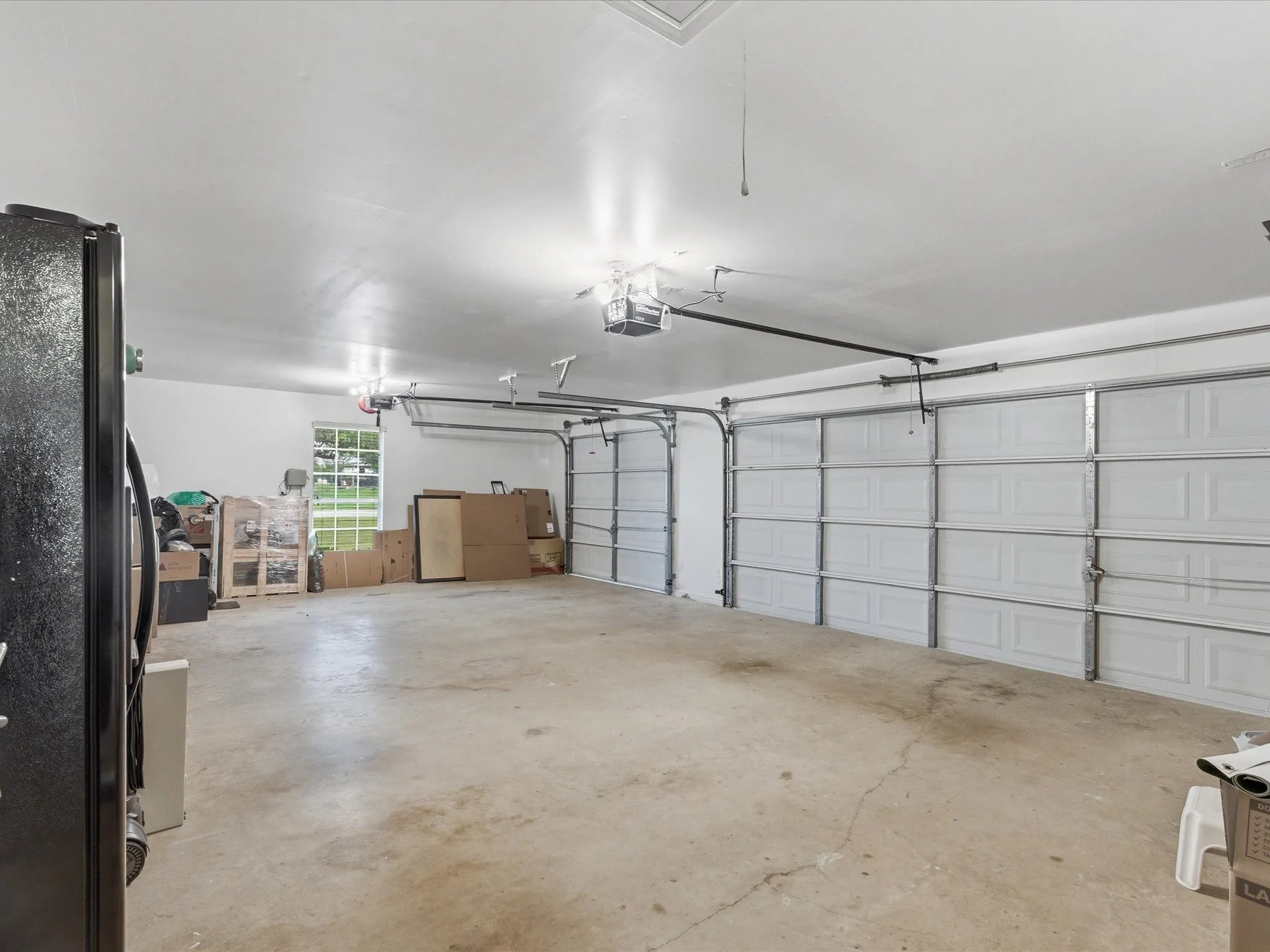 The property features an expansive garage with concrete flooring, two overhead garage doors, and a window providing natural light