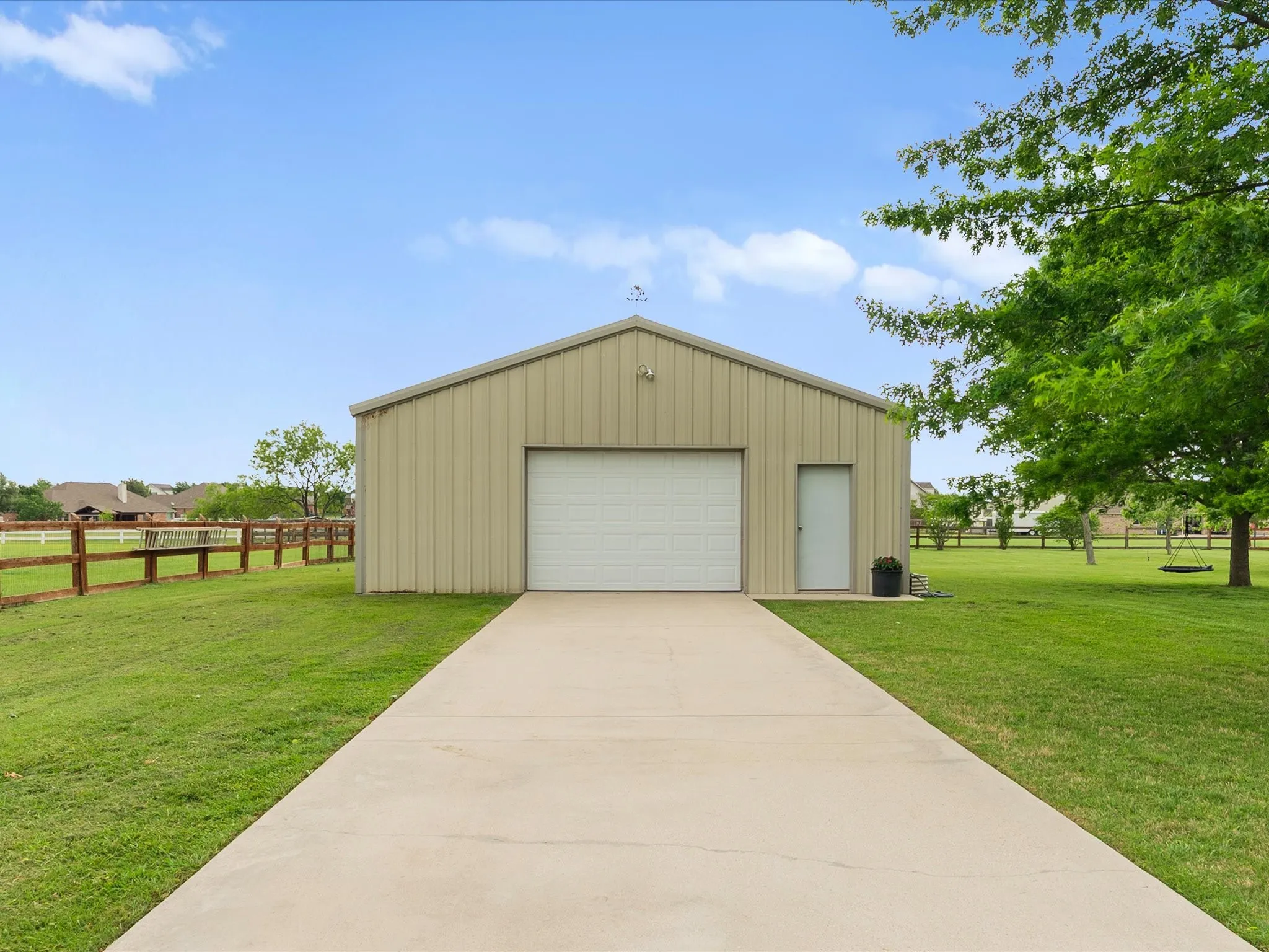 This property features a spacious metal outbuilding with a large garage door, a side entry door, and a concrete driveway