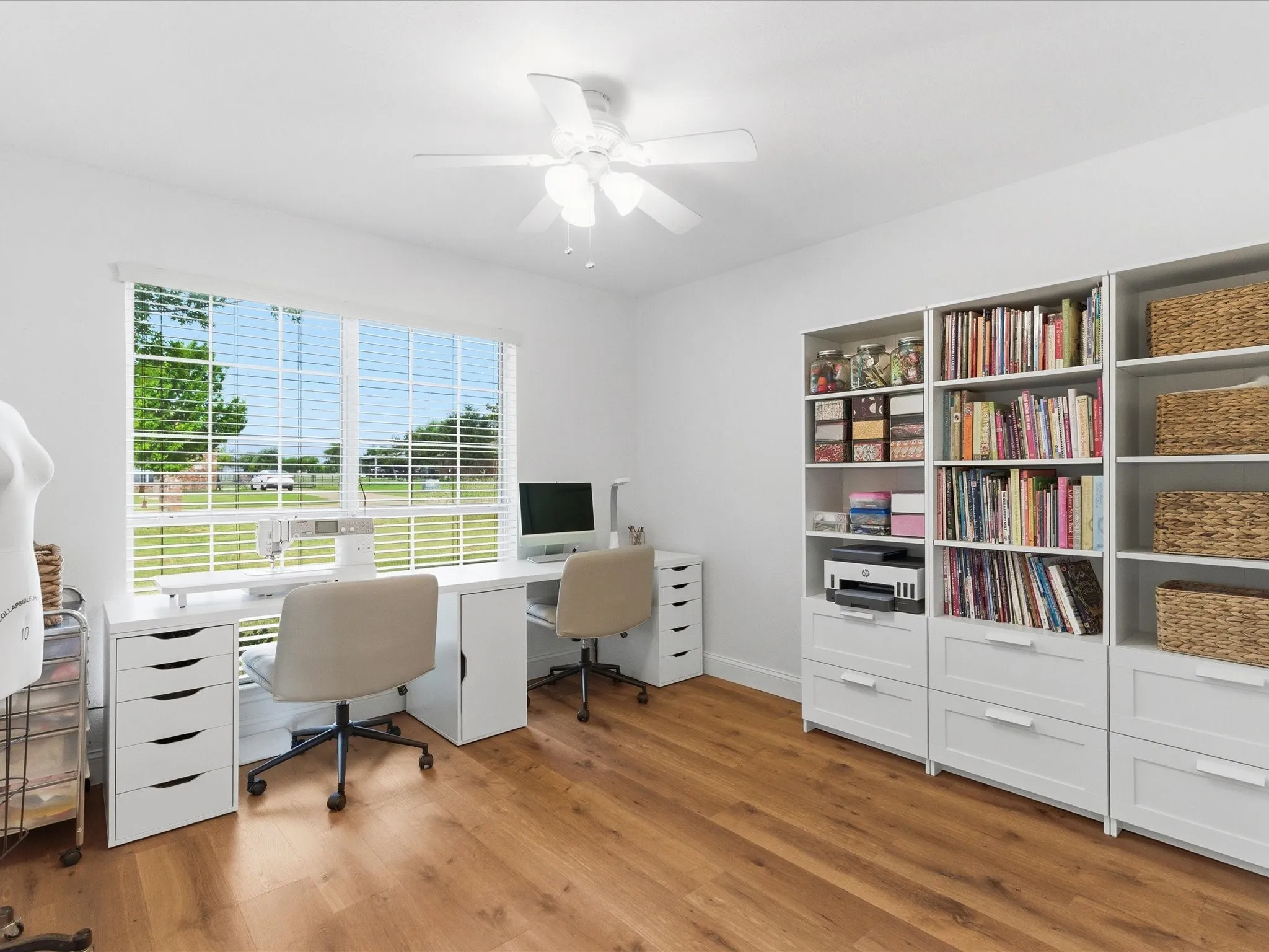 This bright room features a large window, a ceiling fan, and hardwood style flooring
