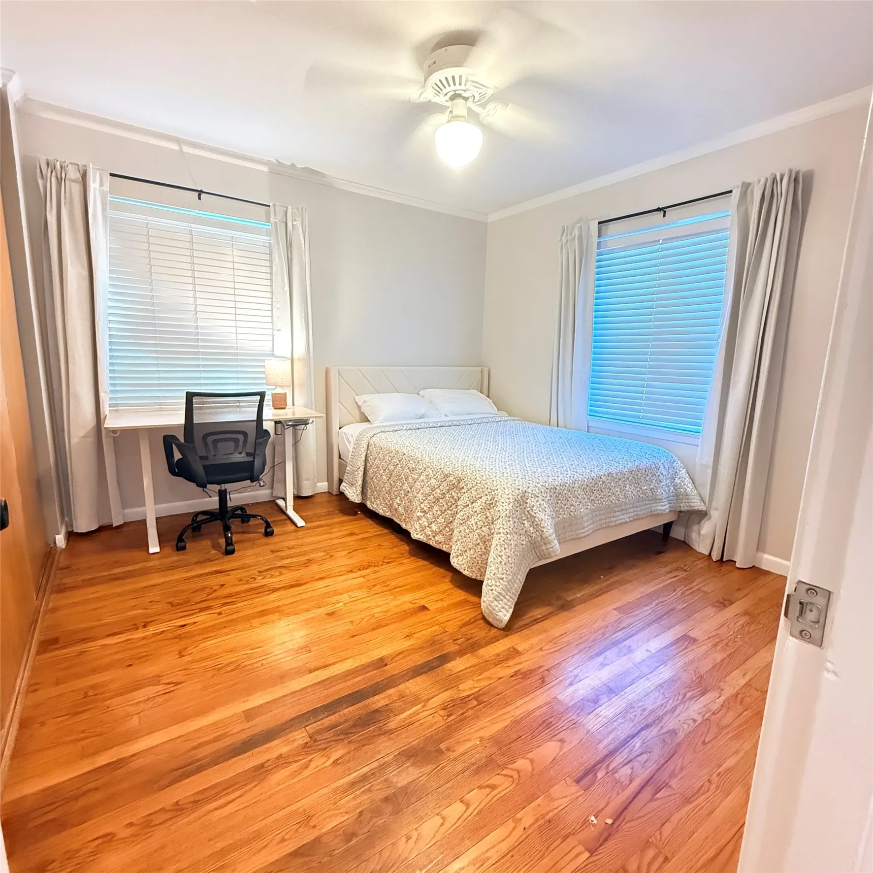 This room features hardwood flooring, white walls, and a ceiling fan