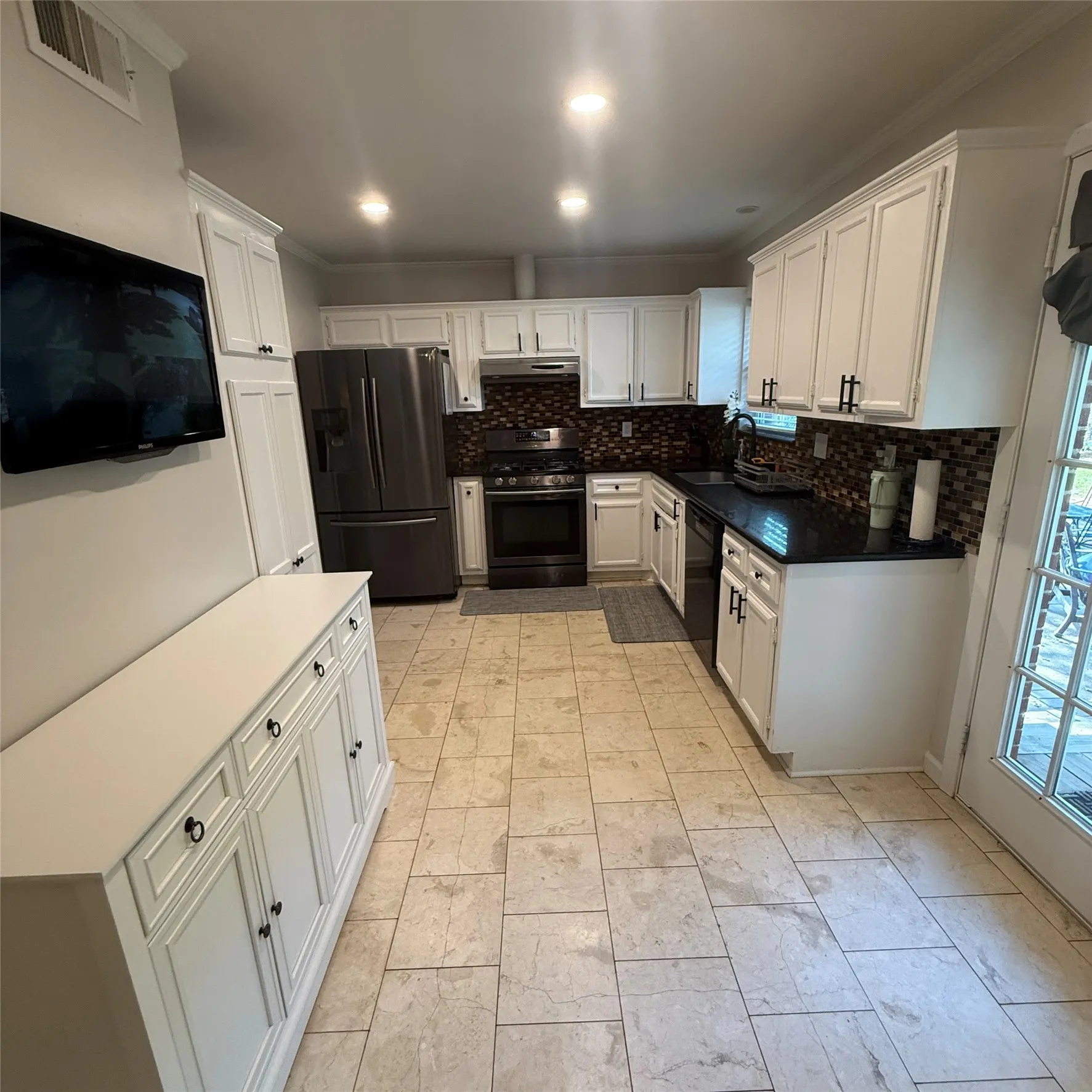 The kitchen features white cabinetry, dark countertops, and a tiled backsplash