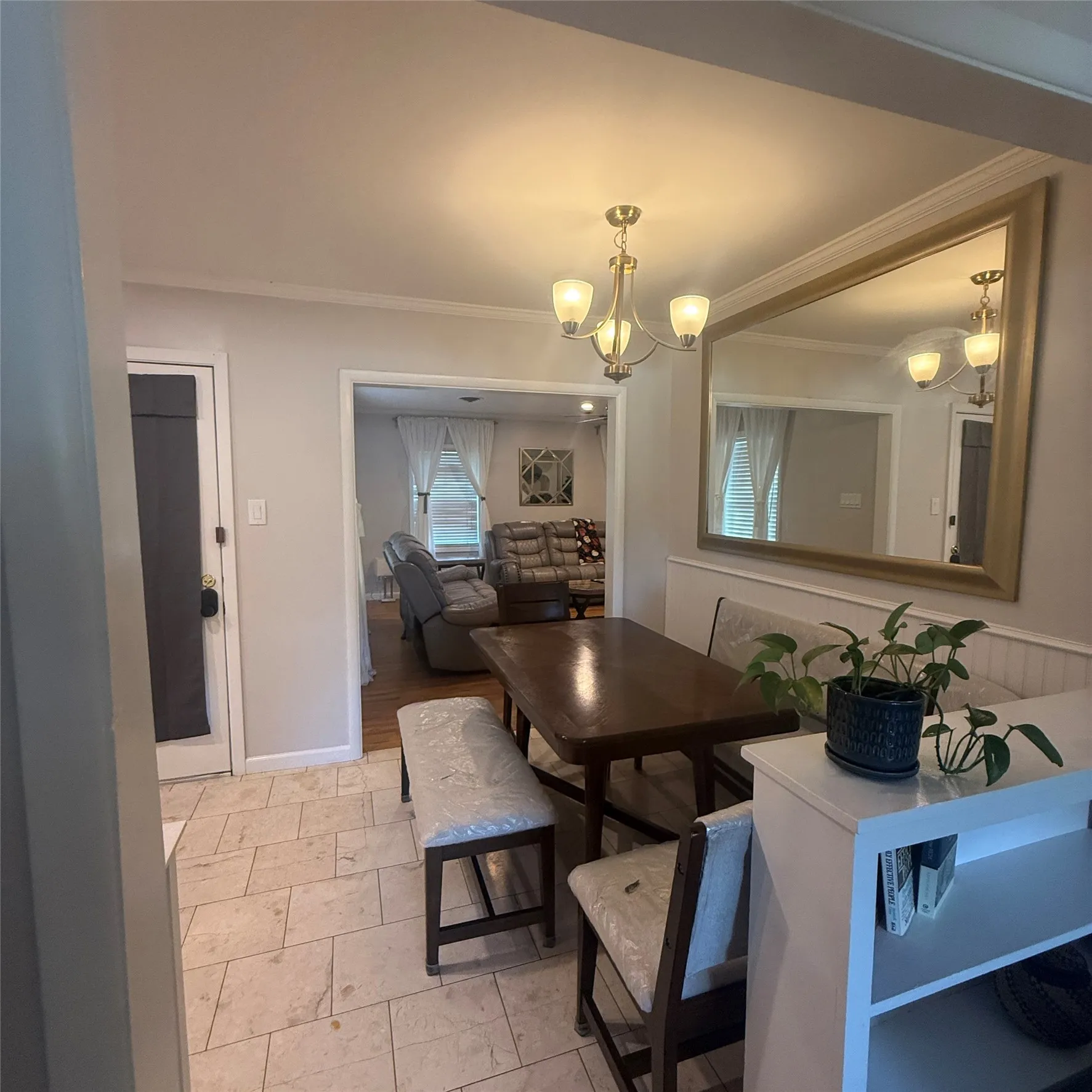 Dining area featuring a chandelier, tile flooring, and wainscoting