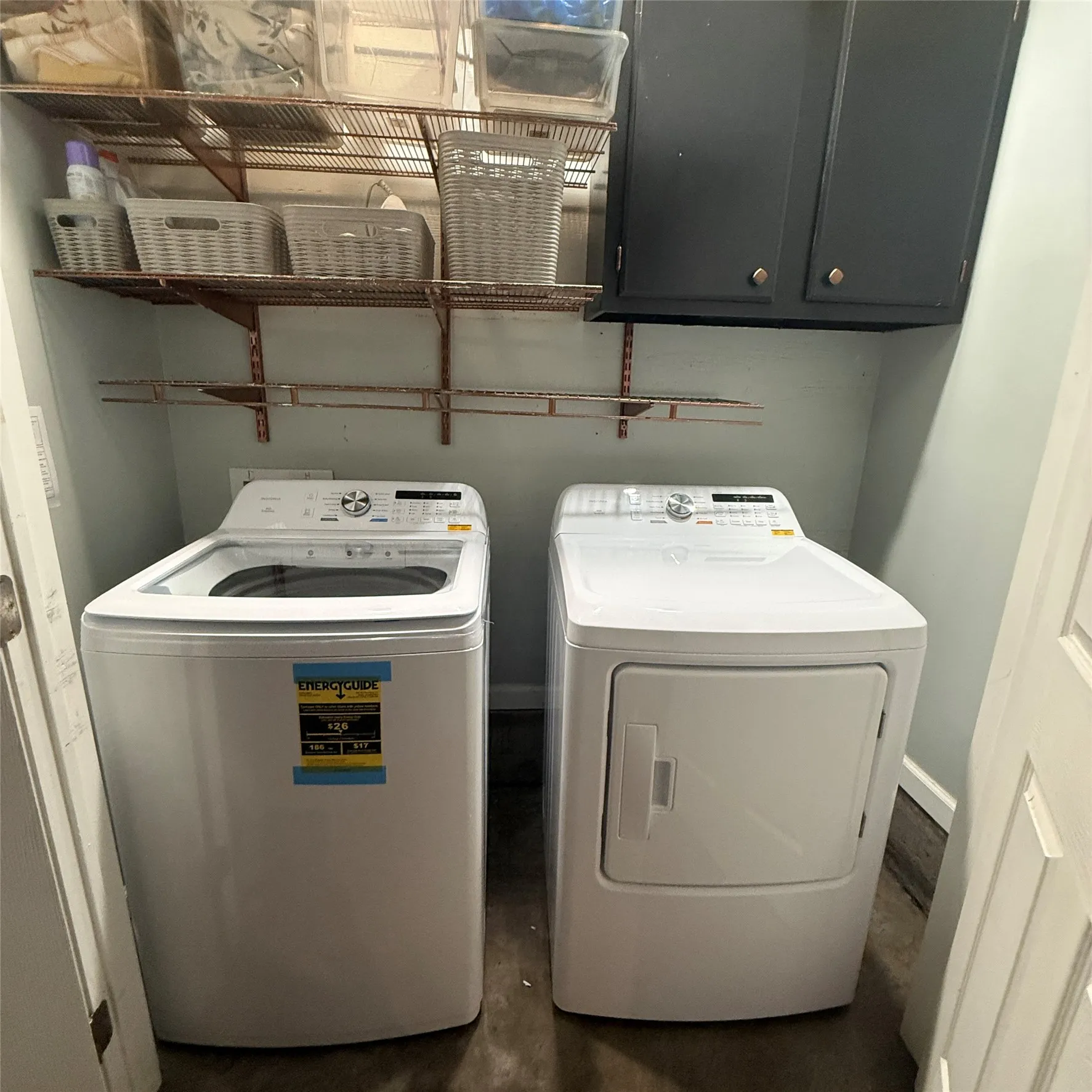 The utility area features a top-loading washing machine and a front-loading dryer, complemented by overhead wire shelving and dark cabinetry