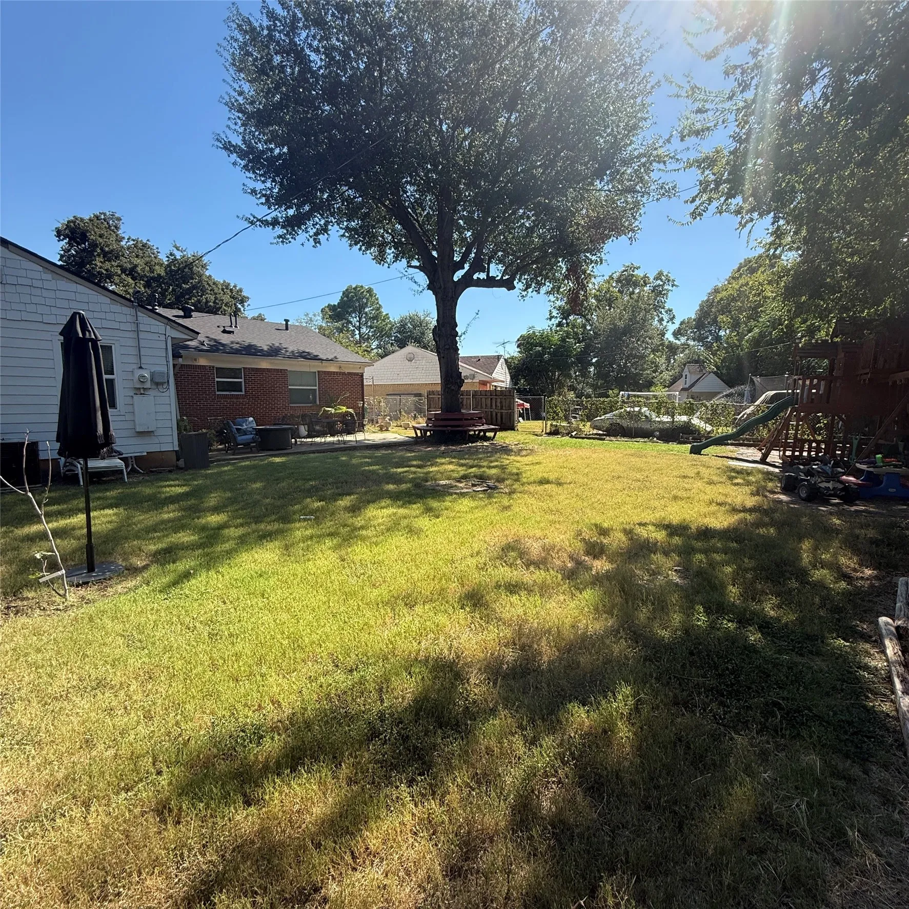 Expansive grassy yard area with mature trees and visible roofing