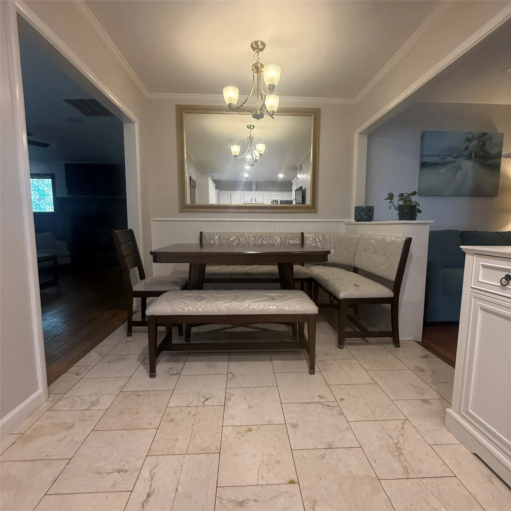 The dining area features tiled flooring, a decorative chandelier, and a large mirror