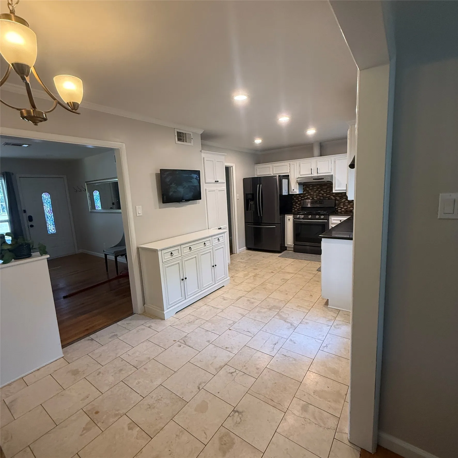 The kitchen features black appliances, white cabinetry, and recessed lighting