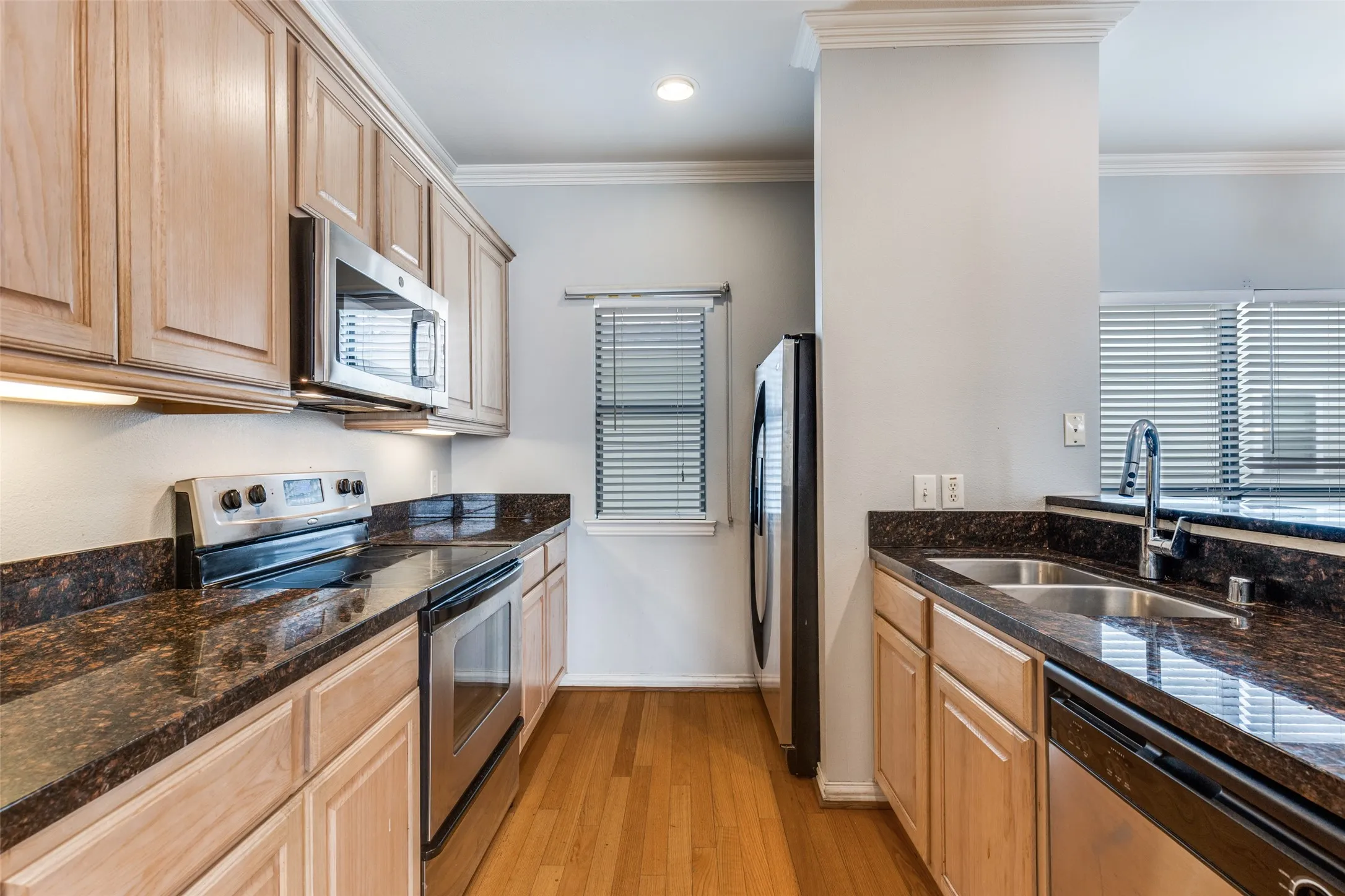The kitchen features hardwood floors, granite countertops, wood cabinetry, and stainless steel appliances including an oven, microwave, dishwasher, and refrigerator