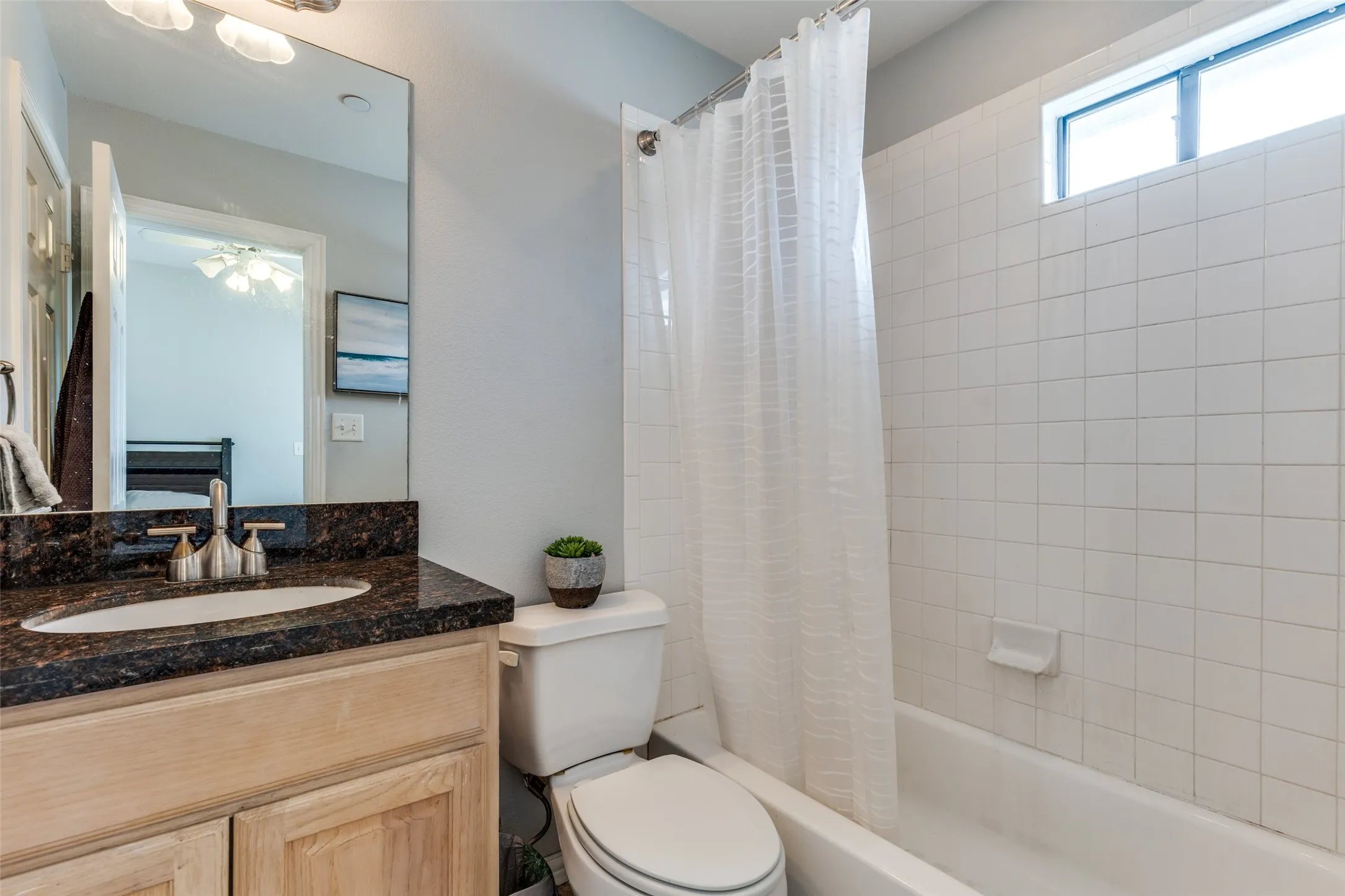 Bathroom featuring a vanity with a dark countertop and an undermount sink, a toilet, and a bathtub with white subway tile surround