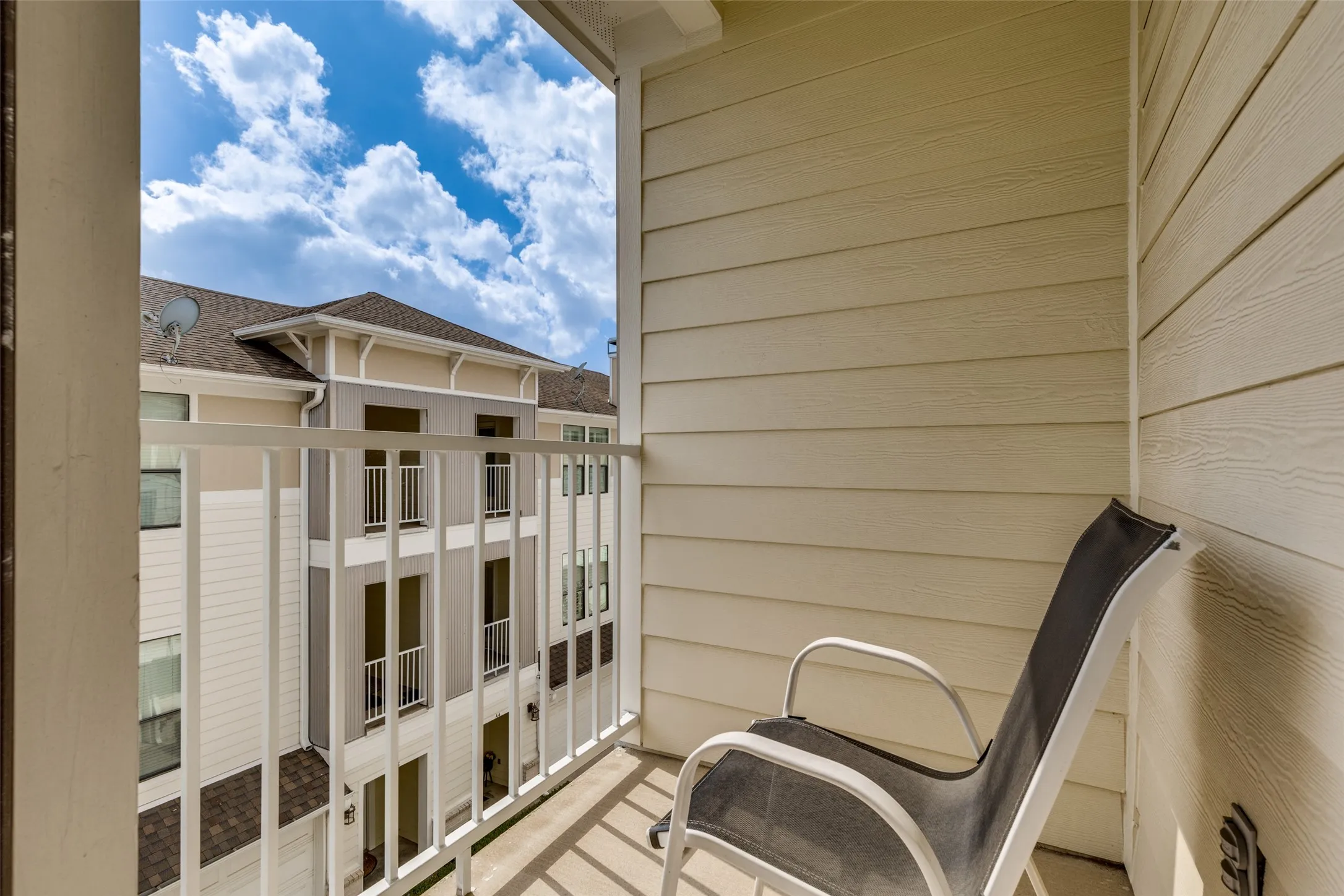 The property features a balcony with white railings, offering a view of a nearby building with balconies