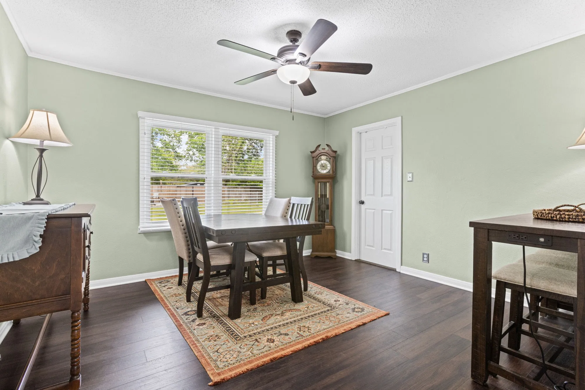 Dining room with dark wood-type flooring, ceiling fan, ornamental molding, and a textured ceiling