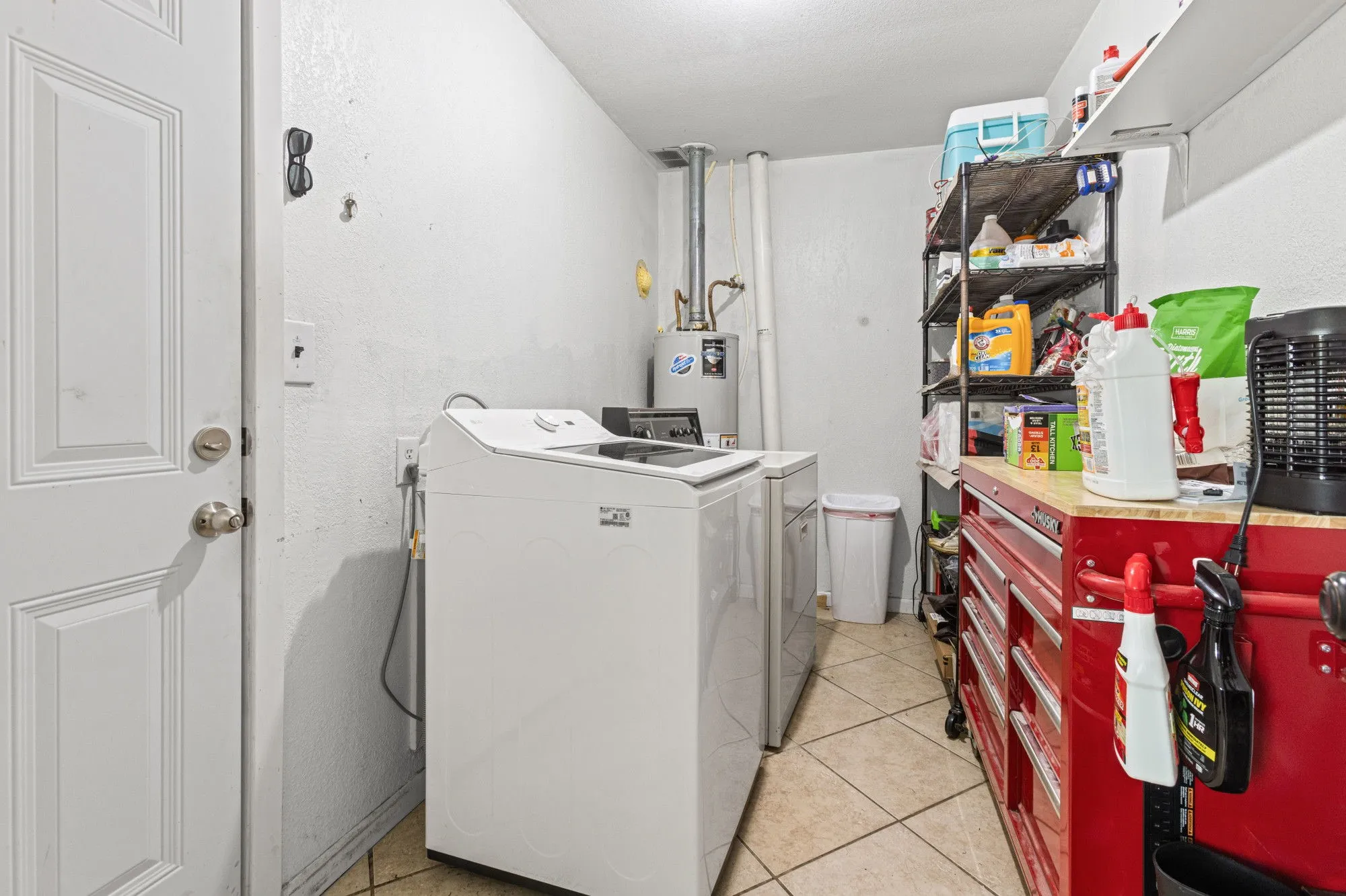 Laundry room featuring water heater, washer and clothes dryer, and light tile patterned floors