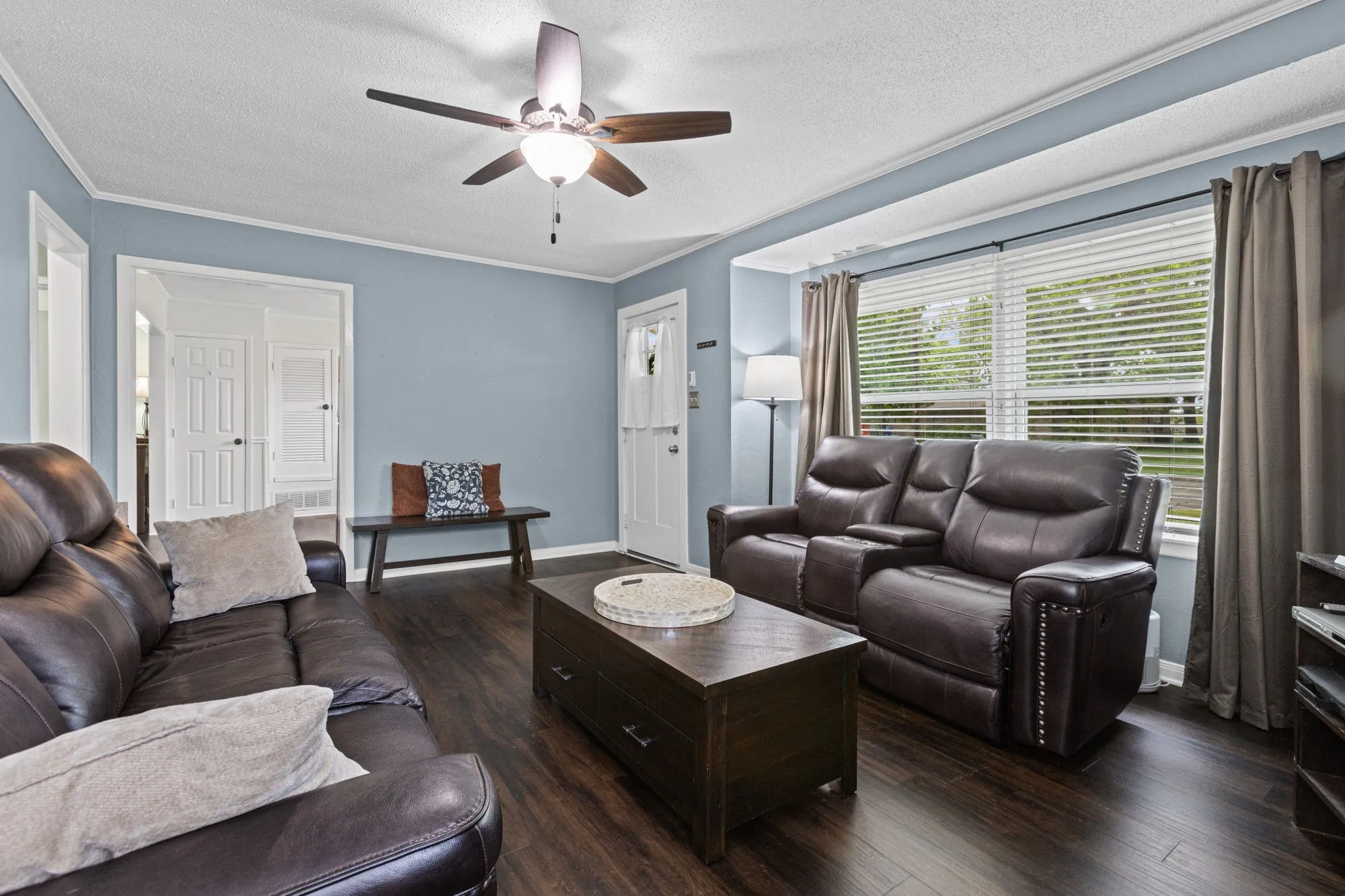 Living room featuring dark wood-style floors, a textured ceiling, crown molding, and ceiling fan