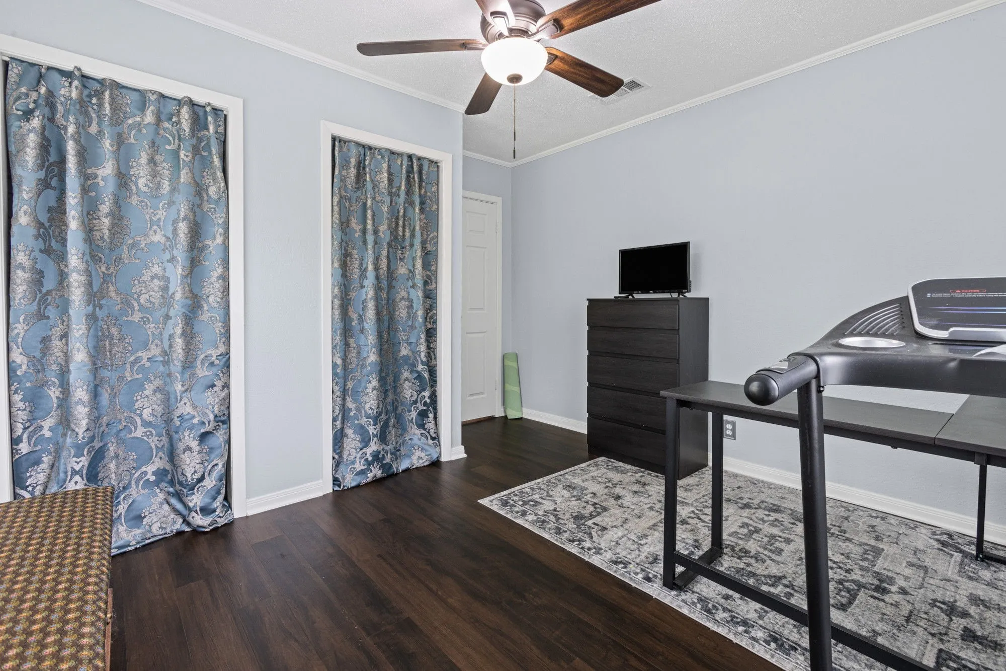Bedroom with ornamental molding, dark wood-style flooring, and ceiling fan