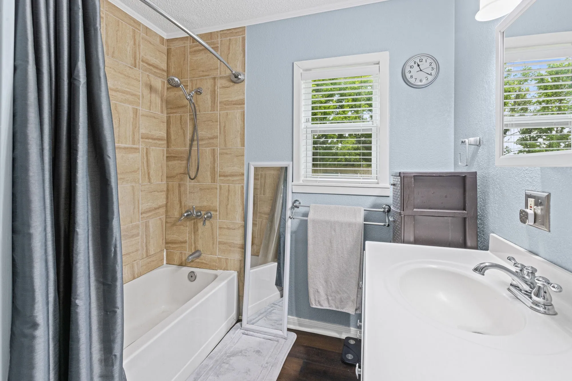 Bathroom featuring shower / bathtub combination with curtain, vanity, a textured ceiling, a textured wall, and dark wood finished floors