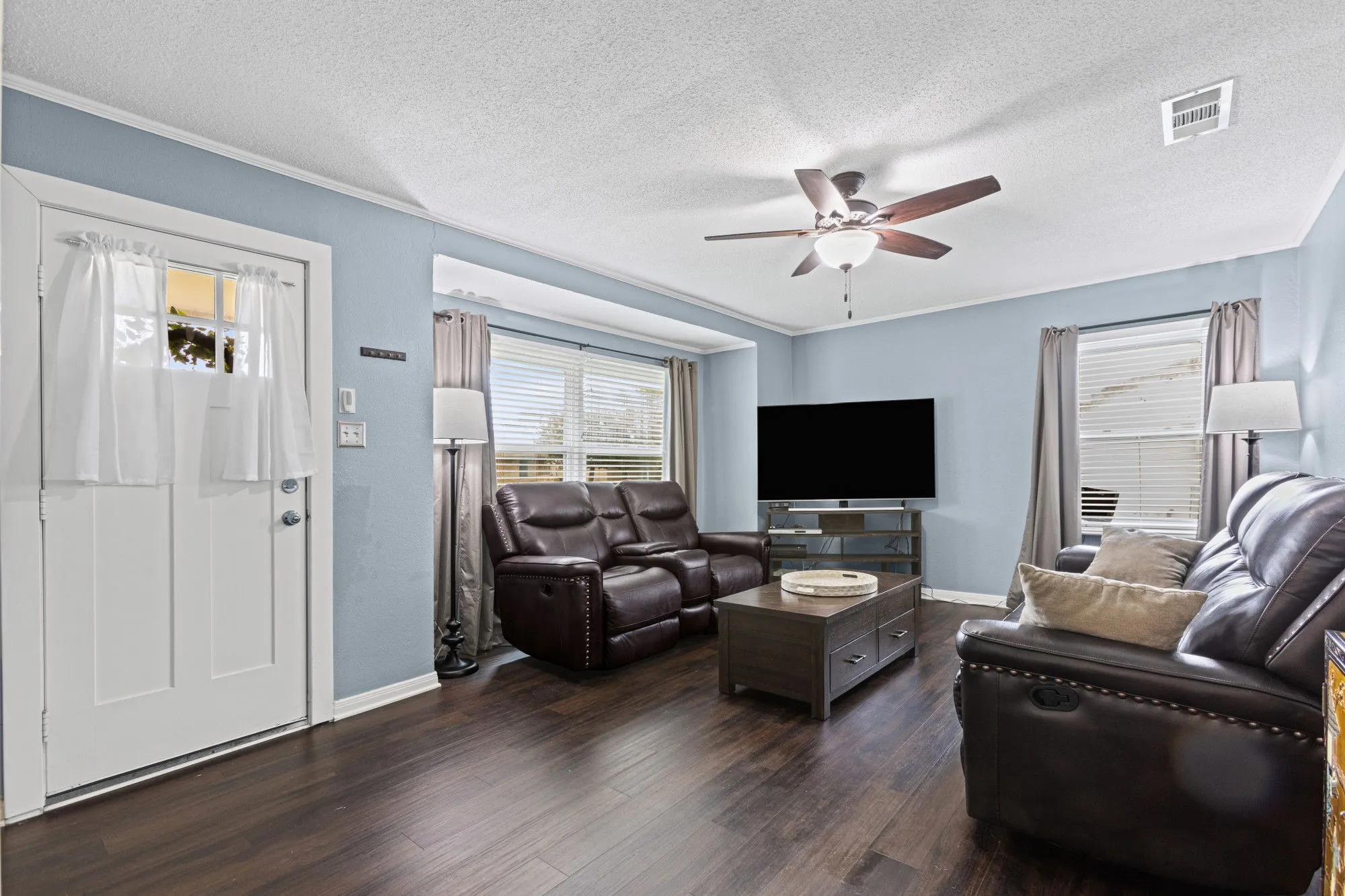 Living area with dark wood-style floors, a textured ceiling, a ceiling fan, and crown molding