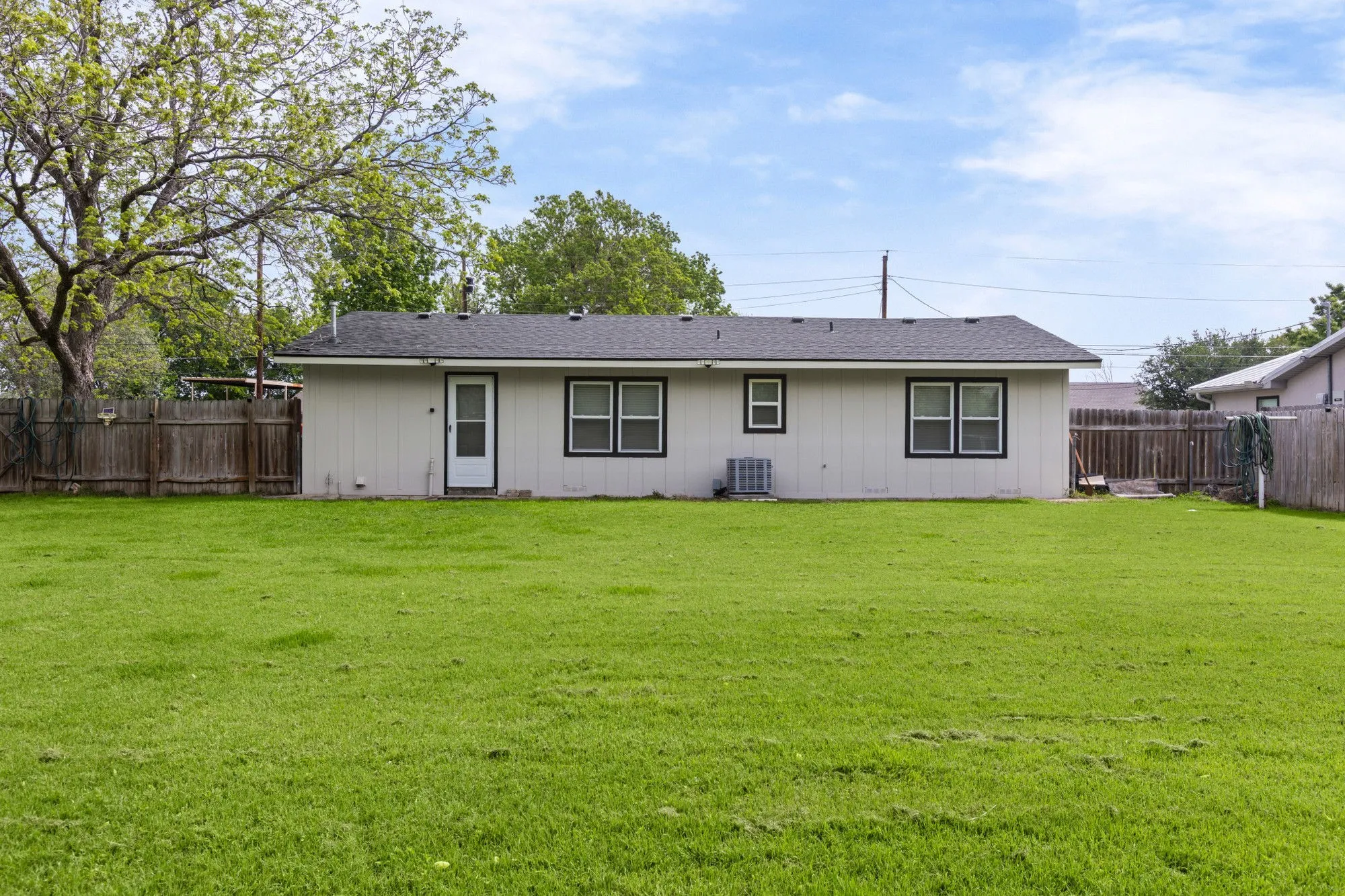 Rear view of property featuring a fenced backyard and a shingled roof