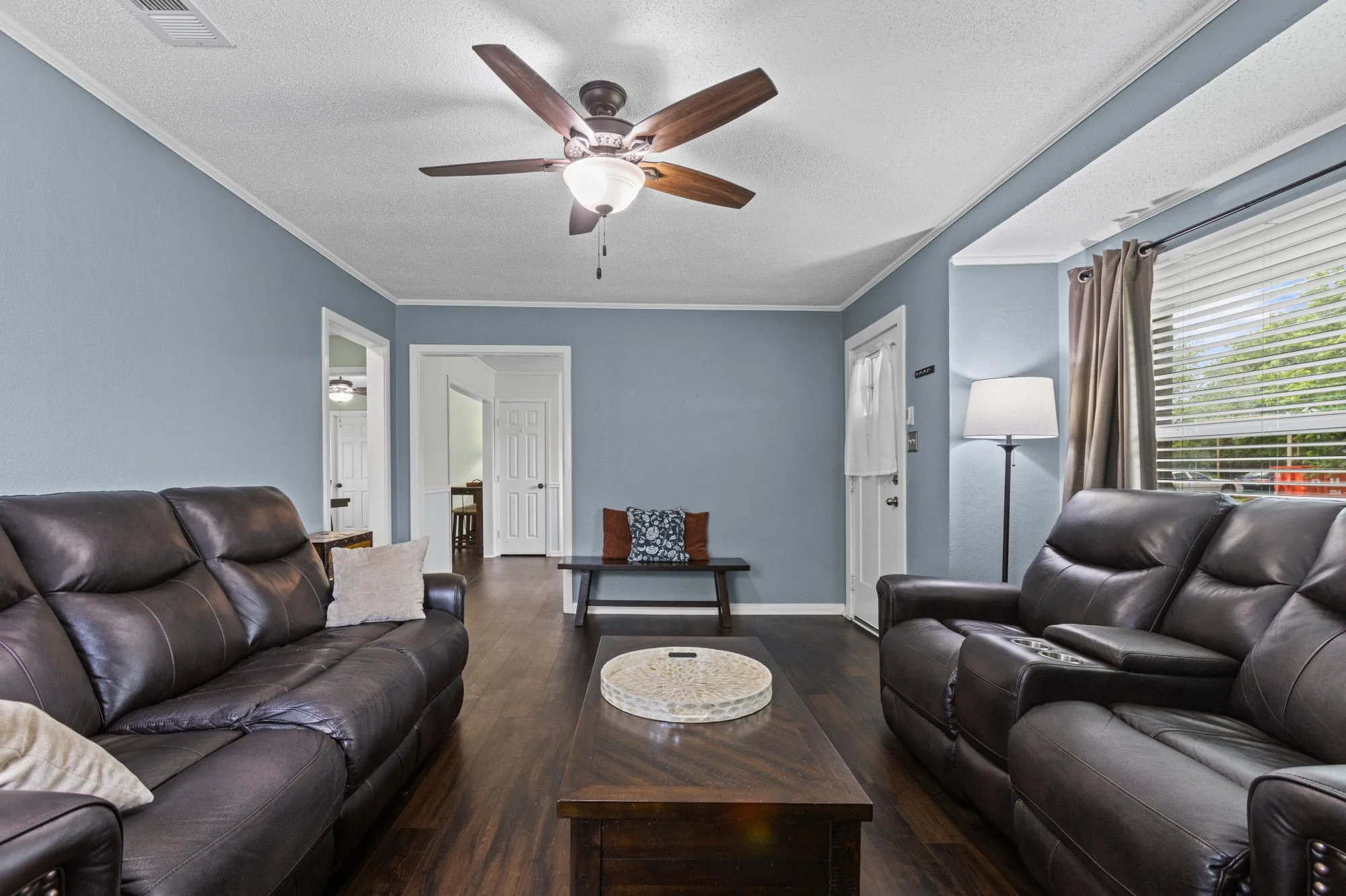 Living area with dark wood-style flooring, a textured ceiling, crown molding, and ceiling fan