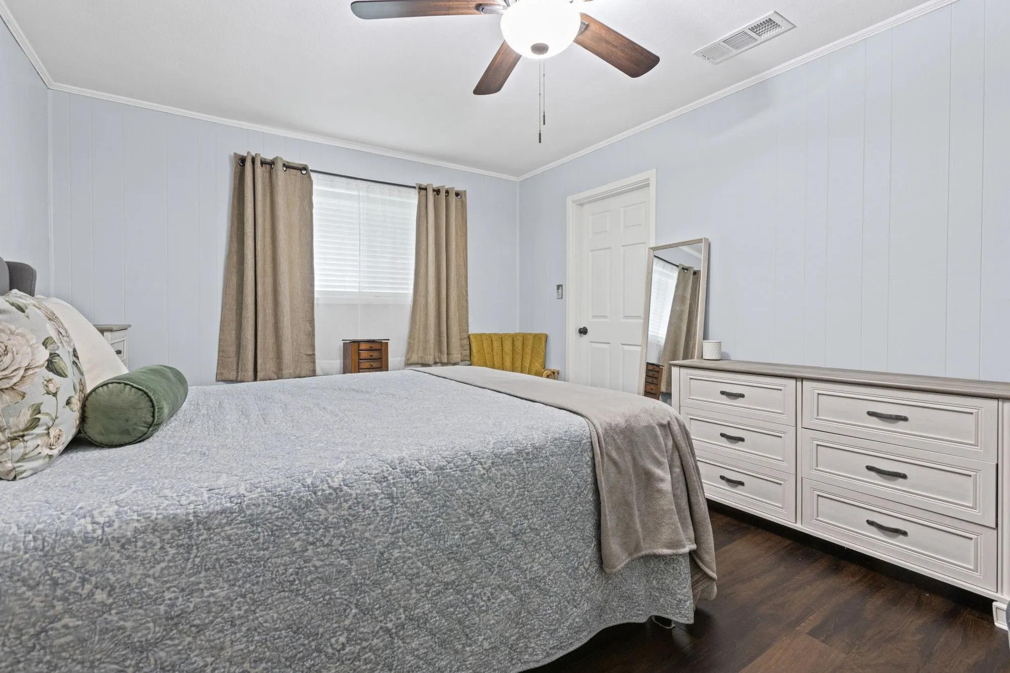 Bedroom featuring ornamental molding, wooden walls, a ceiling fan, and dark wood finished floors