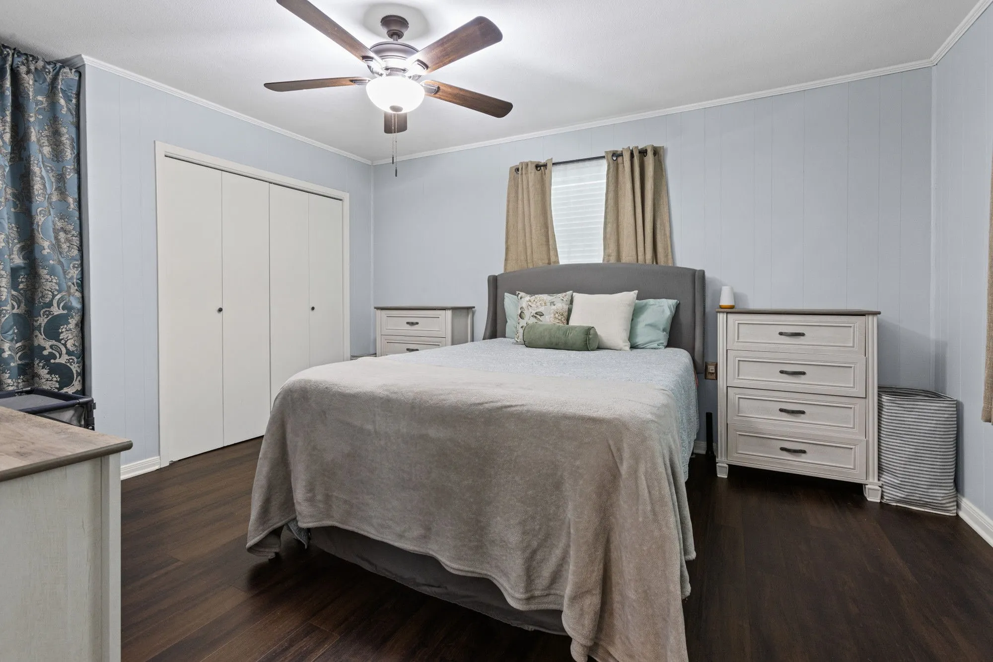 Bedroom with crown molding, dark wood-style flooring, a ceiling fan, a closet, and wood walls