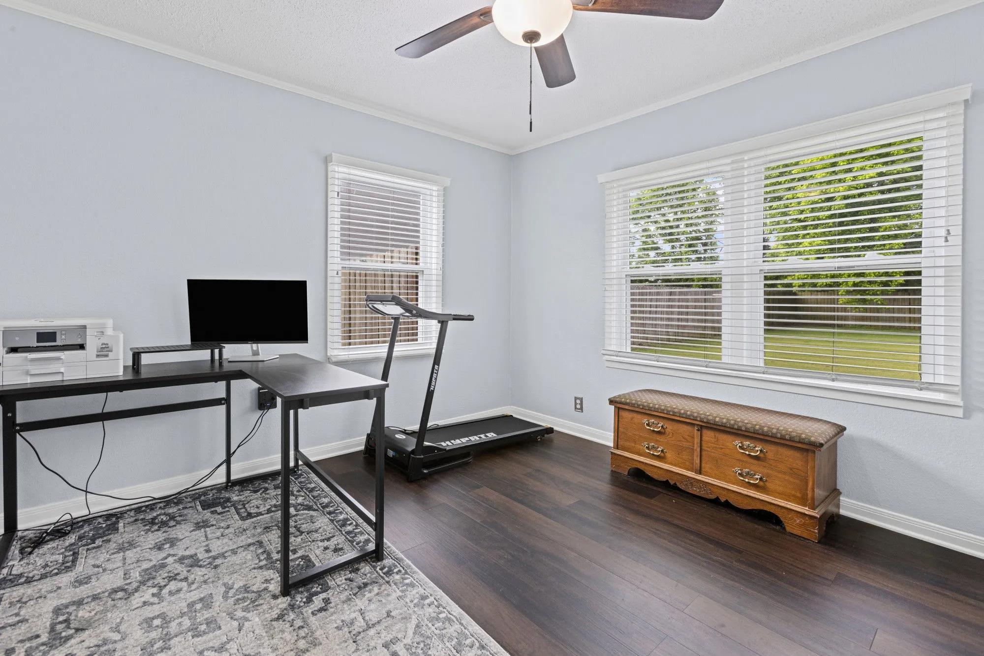 Office with dark wood-style floors, ornamental molding, a ceiling fan, and healthy amount of natural light