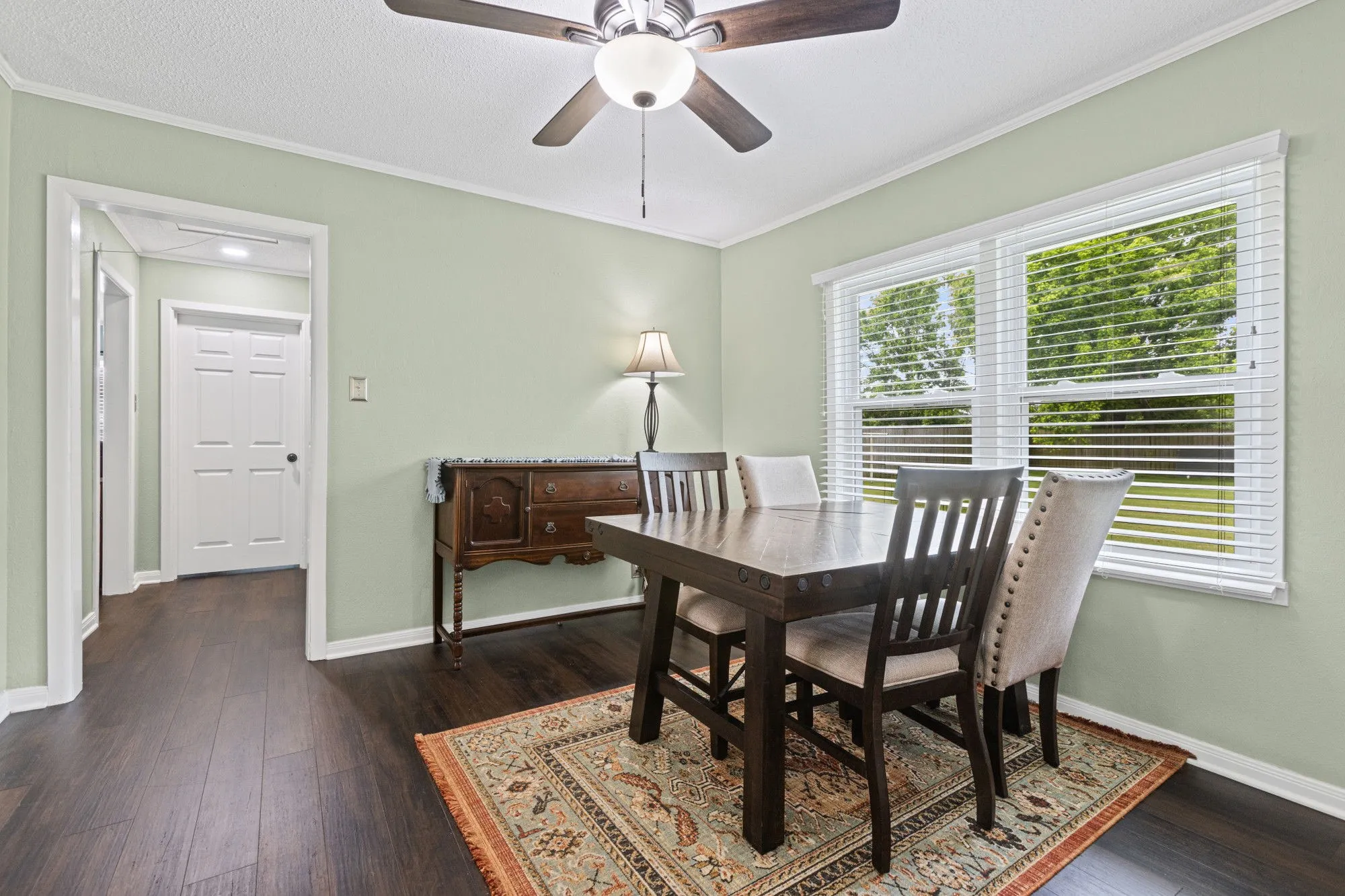 Dining area with dark wood-style floors, ceiling fan, ornamental molding, and a textured ceiling