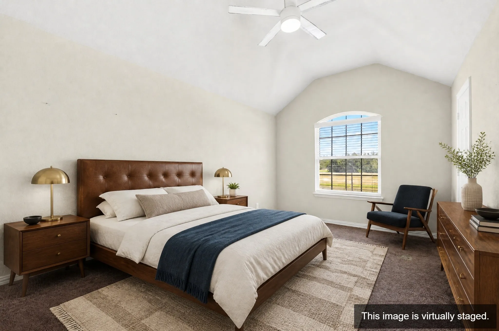 Vaulted ceiling bedroom featuring a ceiling fan, arched window with horizontal blinds, and carpeting