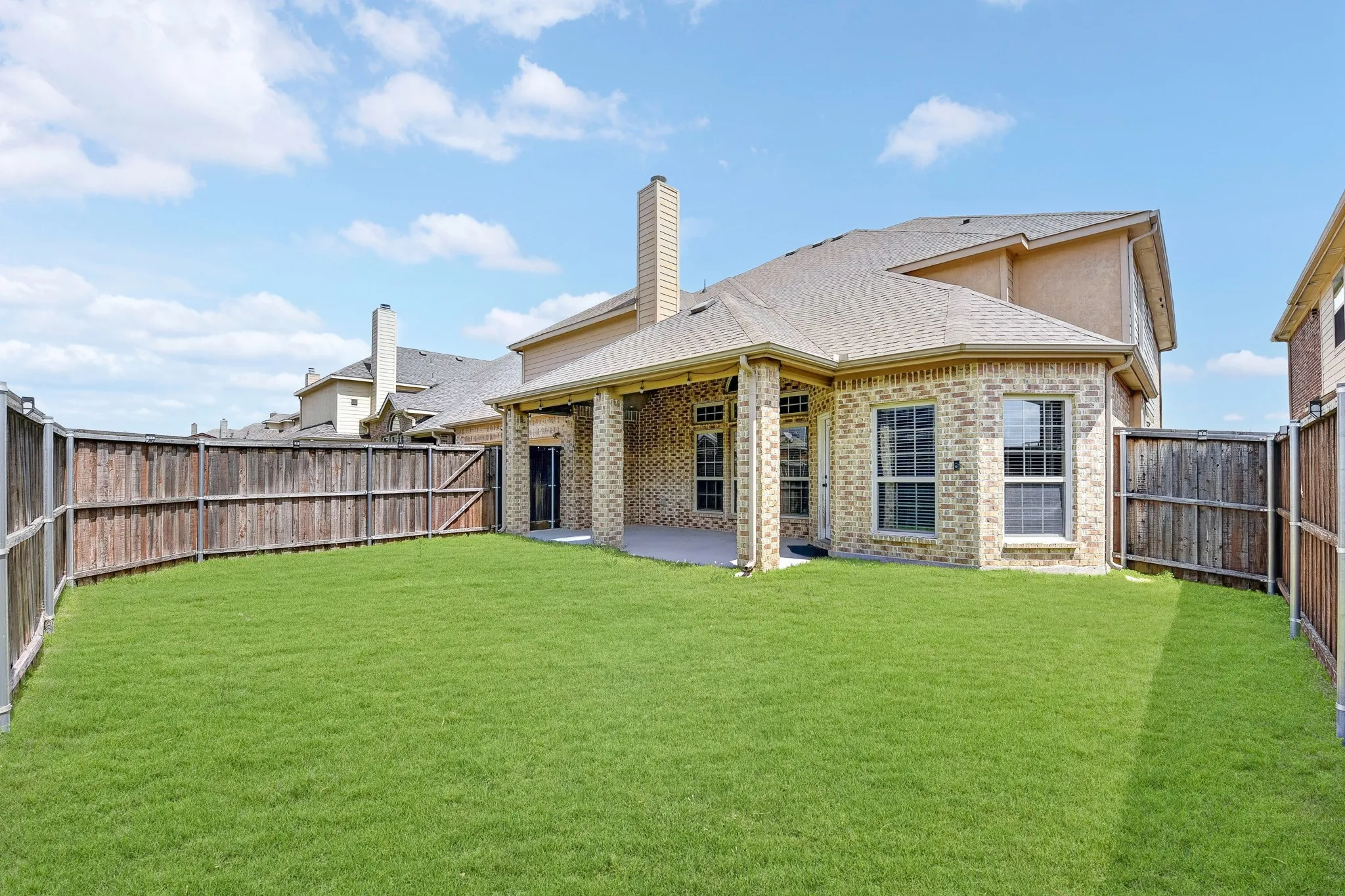 The property features a spacious backyard with a well-maintained lawn, privacy fencing, and a covered patio area