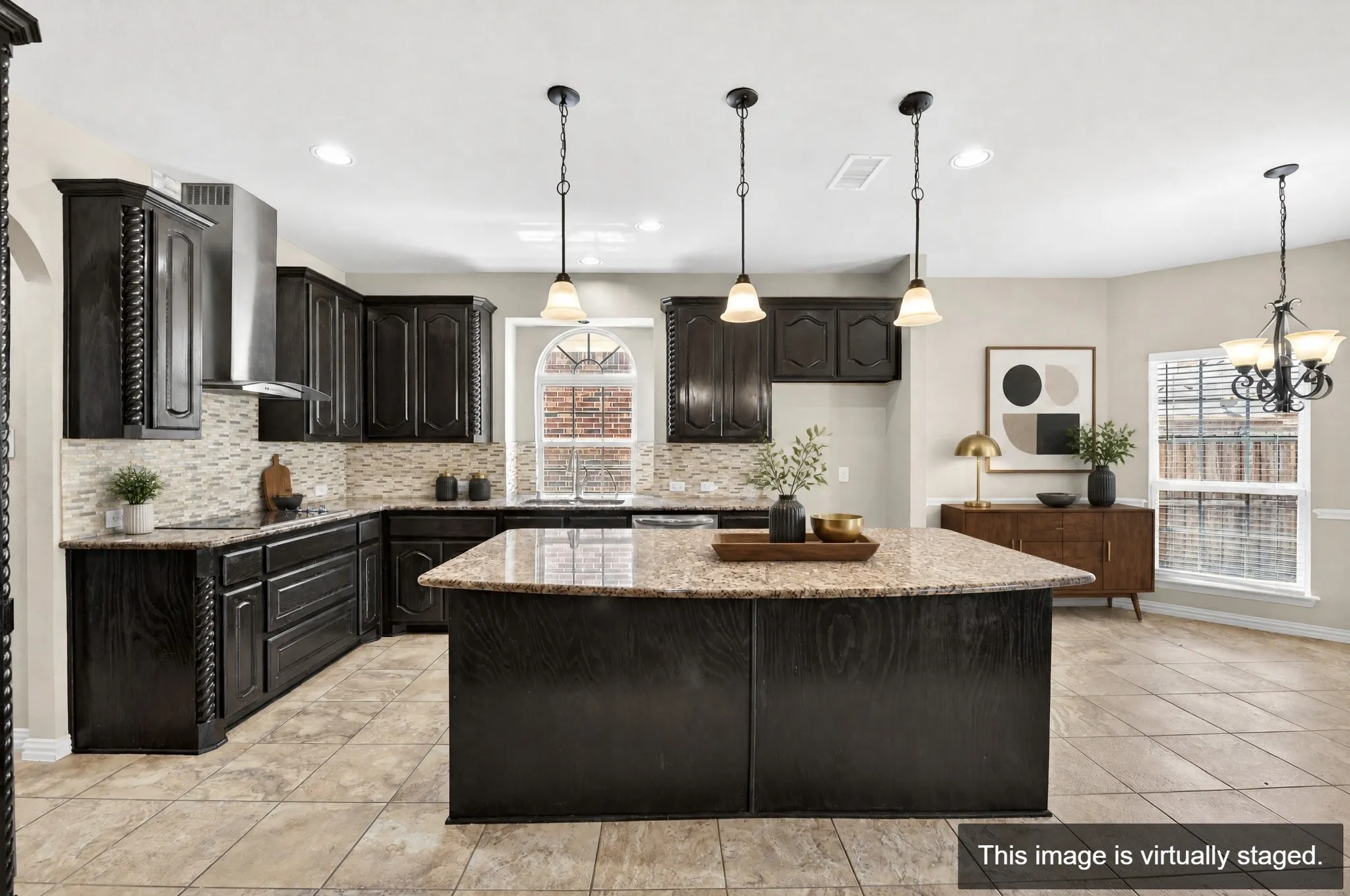 Spacious kitchen featuring dark cabinetry, granite countertops, tile flooring, a central island with pendant lighting, and a stainless steel vent hood