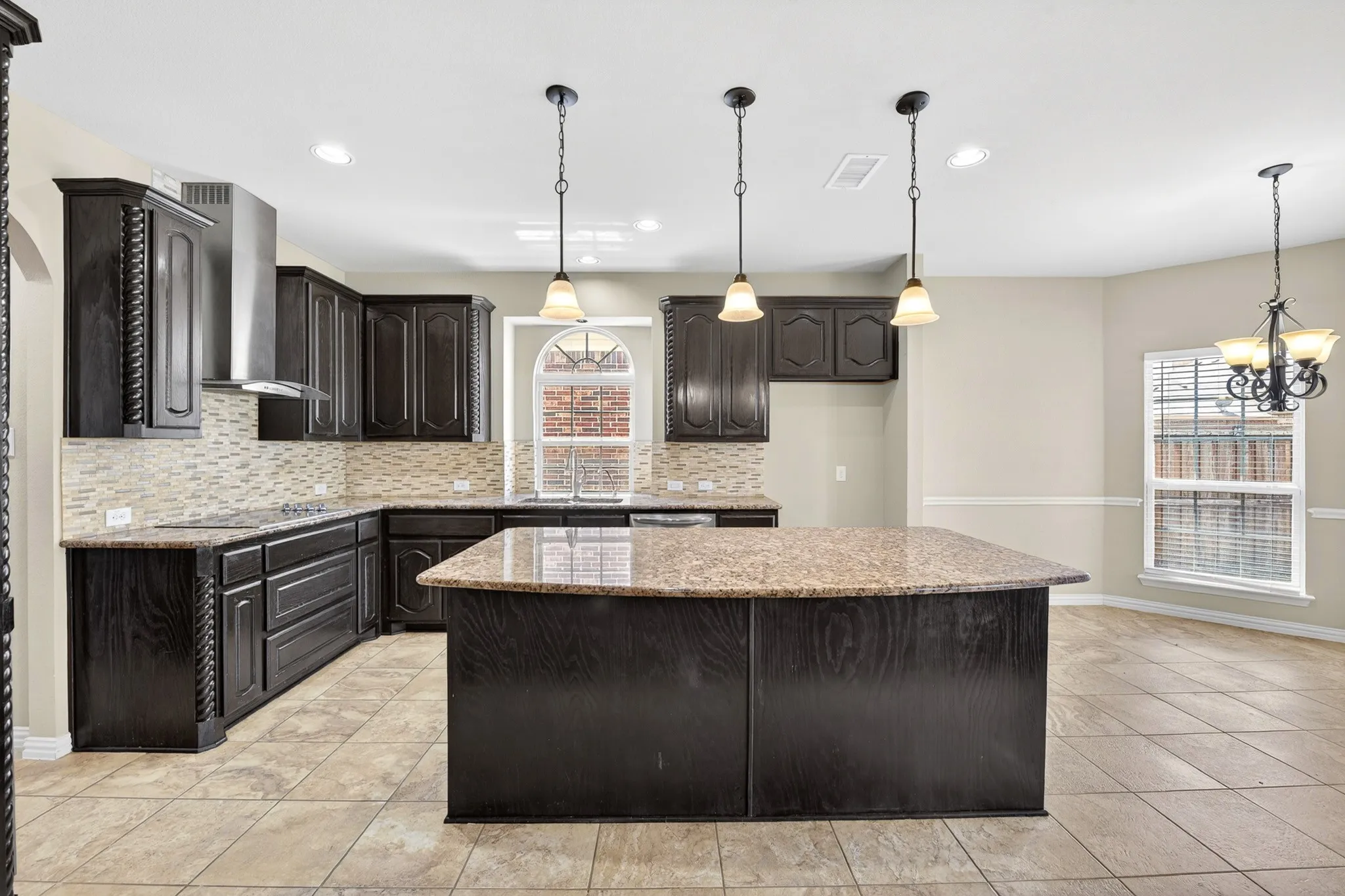 The kitchen features dark wood cabinetry, granite countertops, and a tiled backsplash