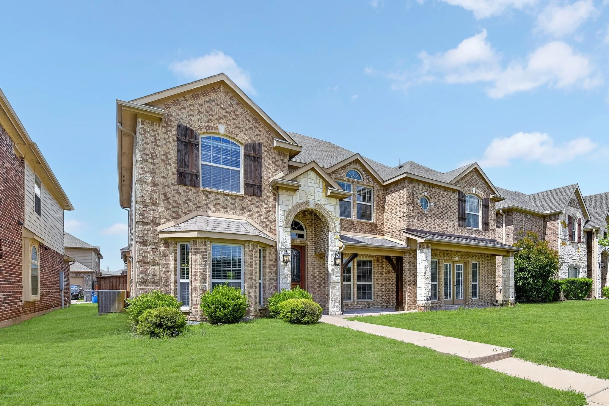 The property features a brick and stone facade, an arched entryway, and a covered porch